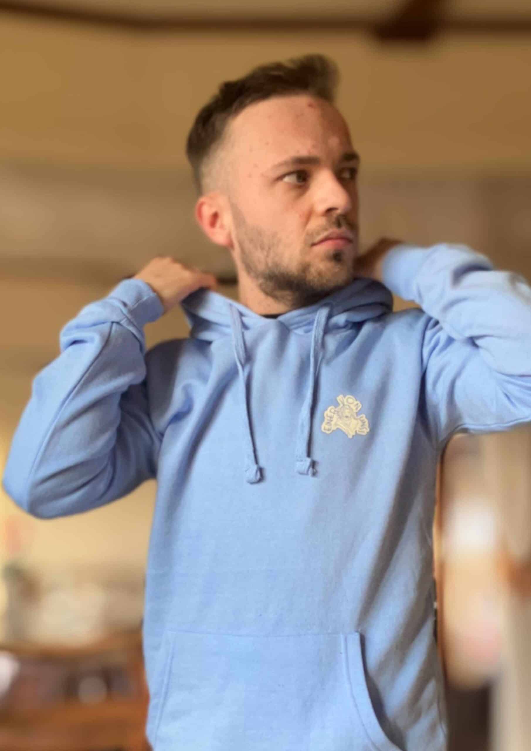 Einer von uns - Hoodie 9 Modischer Mann trägt hellblauen Hoodie mit christlichem Logo, stilvolle Freizeitmode.