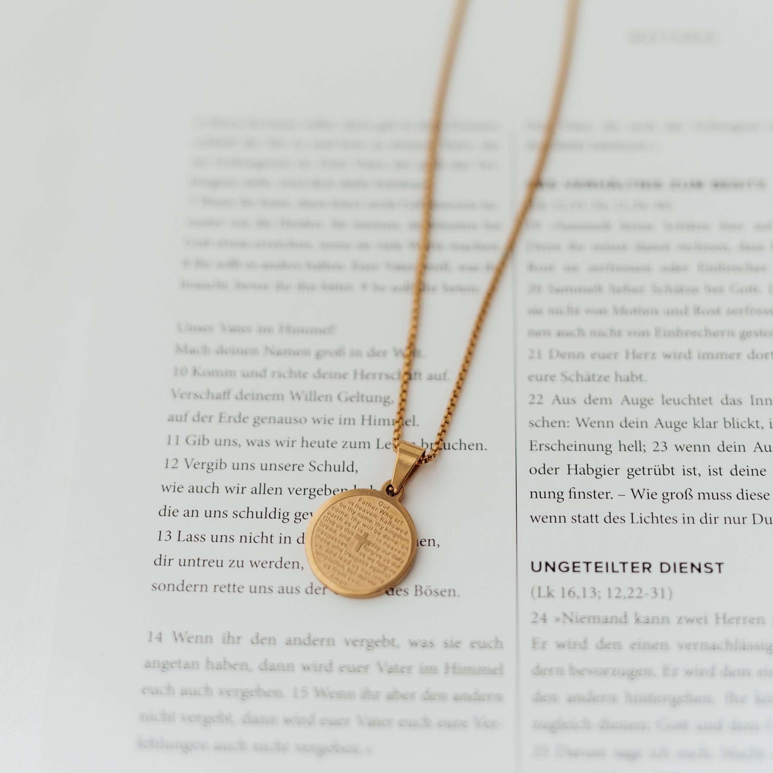 Prayer Necklace | Christliche Kette – Edelstahl vergoldet – Kreuz 16 Gotteshaube mit Kreuz und Bibelvers auf geöffneter Bibel in christlichem Kontext.