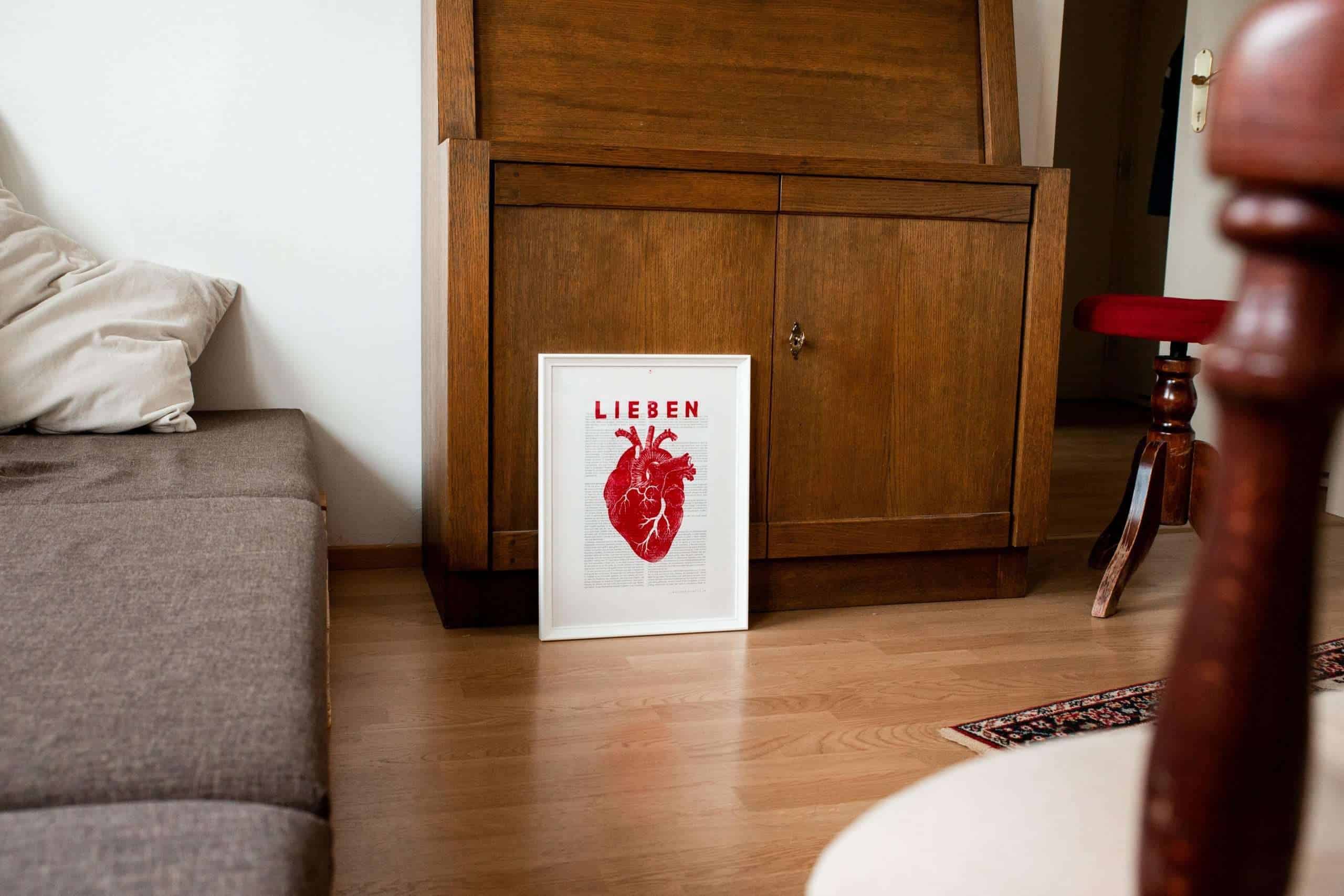 Lieben | Christlicher Kunstdruck – Die Bibel auf Art Prints – DIN A3 – 1. Korintherbrief 12-14 6 Herzbild mit Bibeltext im weißen Rahmen auf Holzmöbel.