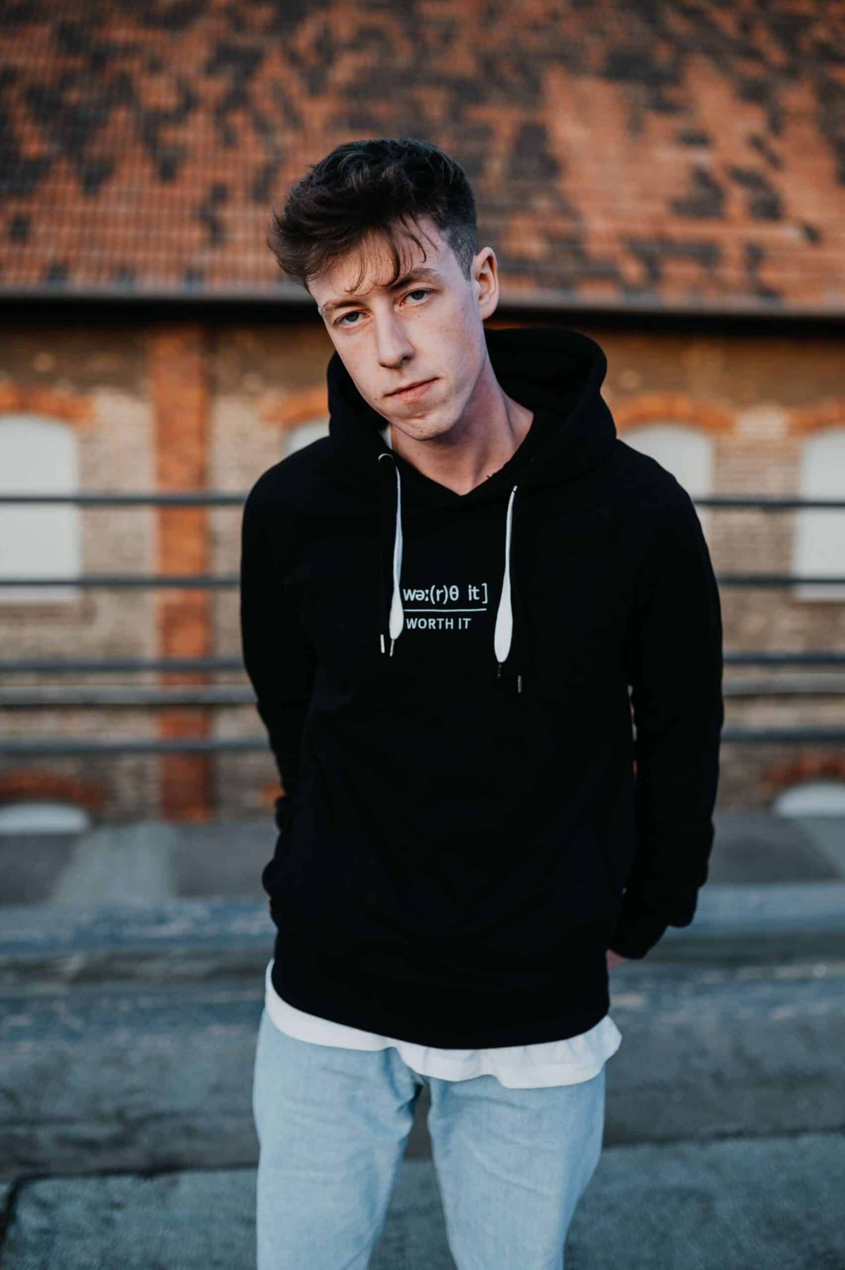 WORTH IT?! Hoodie 9 Modischer junger Mann trägt christliches Hoodie auf Dachterrasse, Streetwear, christliche Mode.