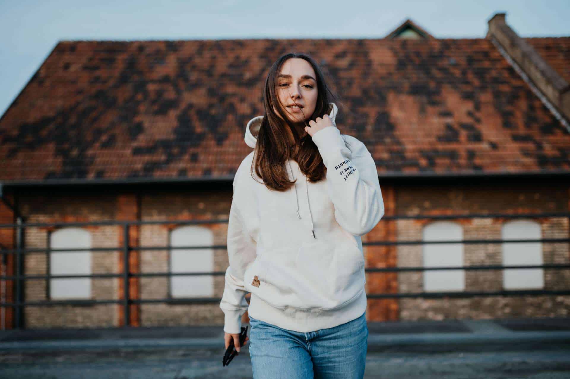 UNITED Hoodie 14 Moderne junge Frau trägt weiße Kapuzenjacke mit christlichem Design, outdoor Lifestyle.