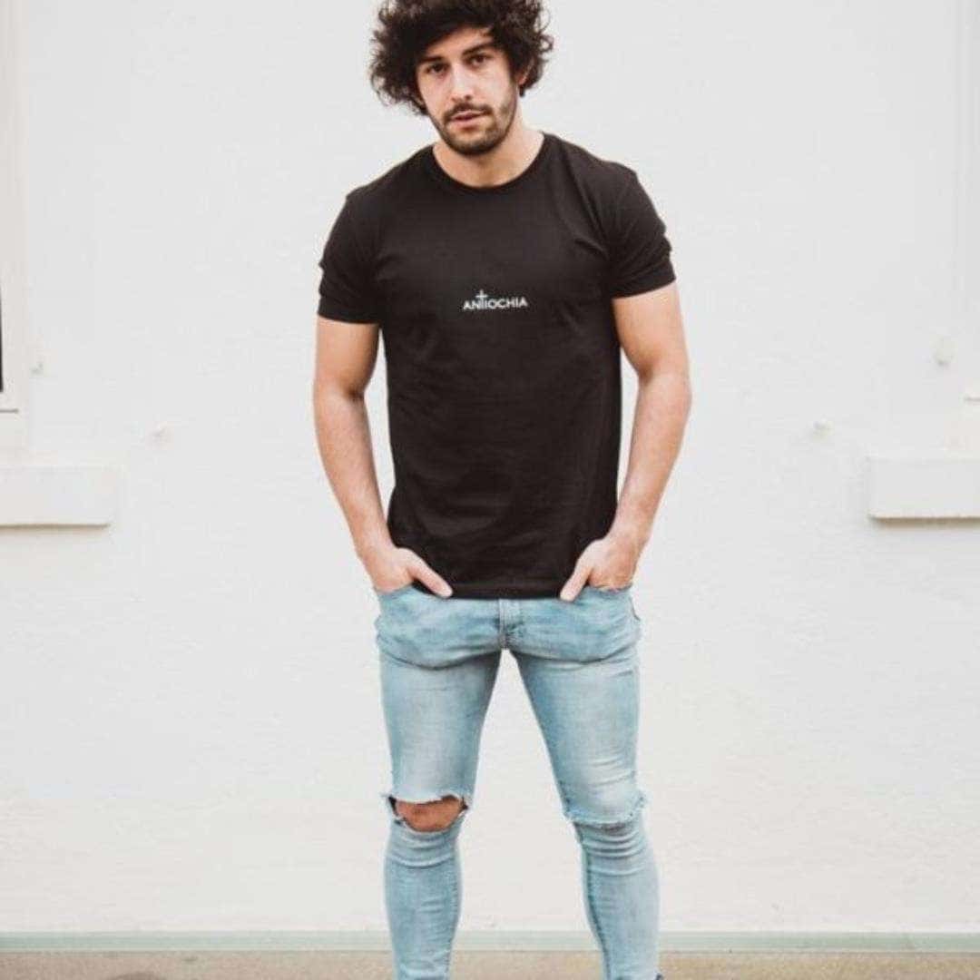 Herren Basic T-Shirt - "Birth" 14 Stylischer junger Mann trägt schwarze Christent-Shirt mit AntiChia-Logo, modisches Streetwear.