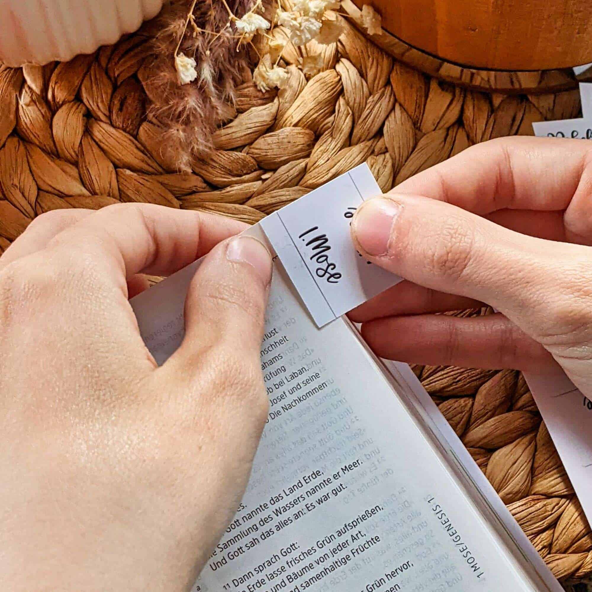 Bibelregister „Marmor“ | Griffregister für die Bibel | Bibel-Griffregister | Selbstklebend | Lettering | Weiß 4 Hände beim Einlegen eines Lesezeichen mit Bibel-Text auf einem Holzkorb, christliche Inspiration.