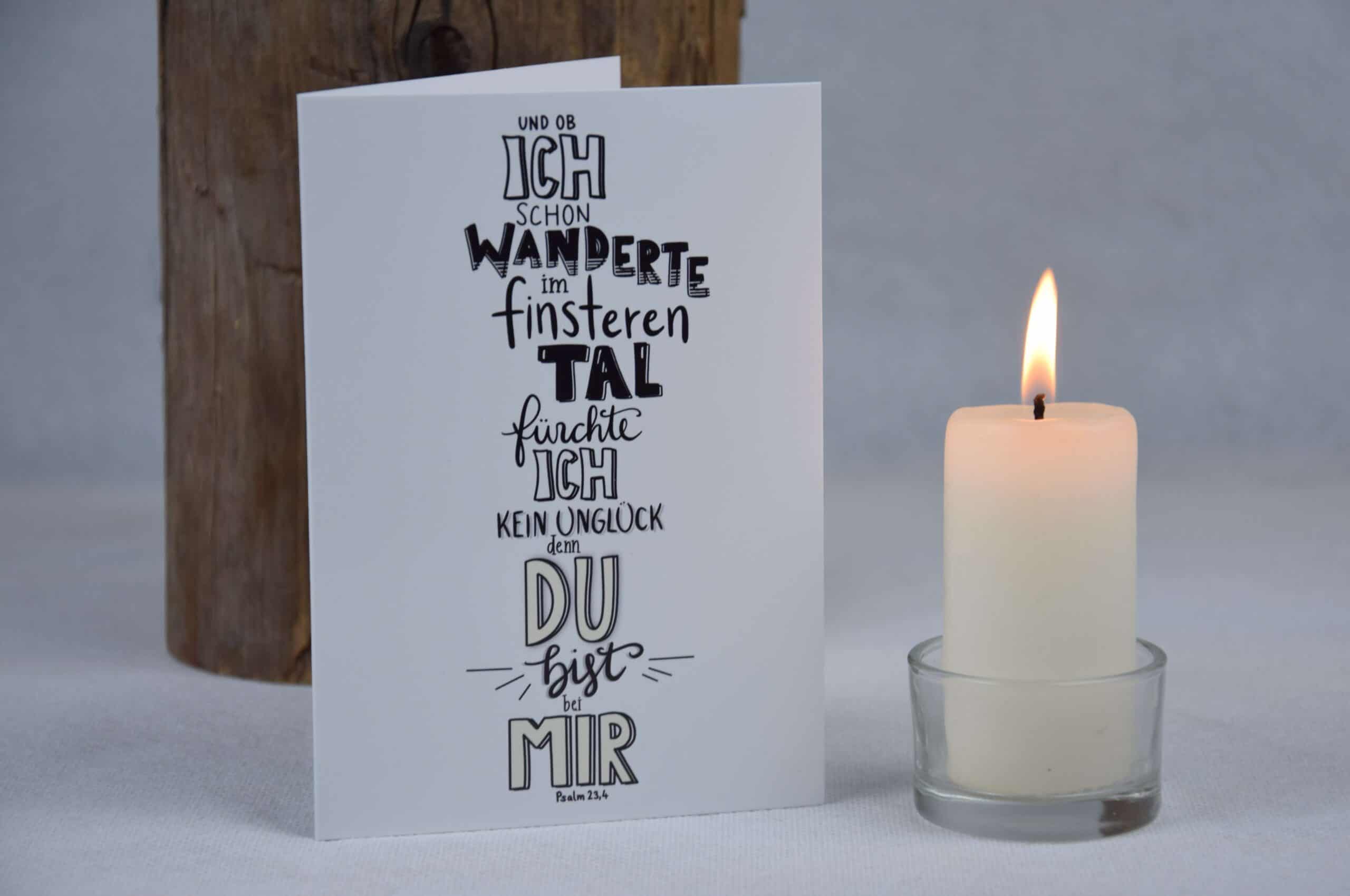 Inspirierende christliche Grußkarte mit Bibelvers, Kerze und Holzdeko auf weißem Tisch.