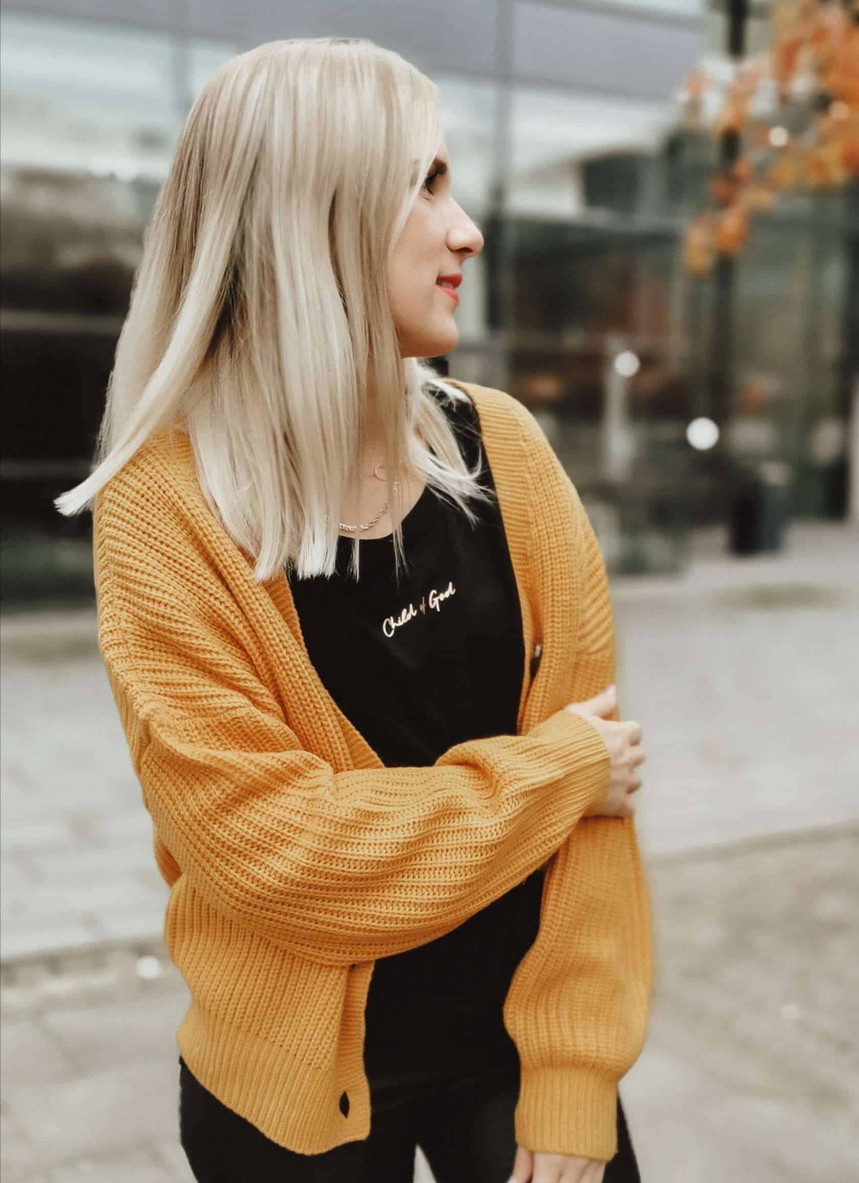 Moderne junge Frau trägt gelbe Strickjacke, streetstyle Look, Stadt, Mode, Lifestyle.