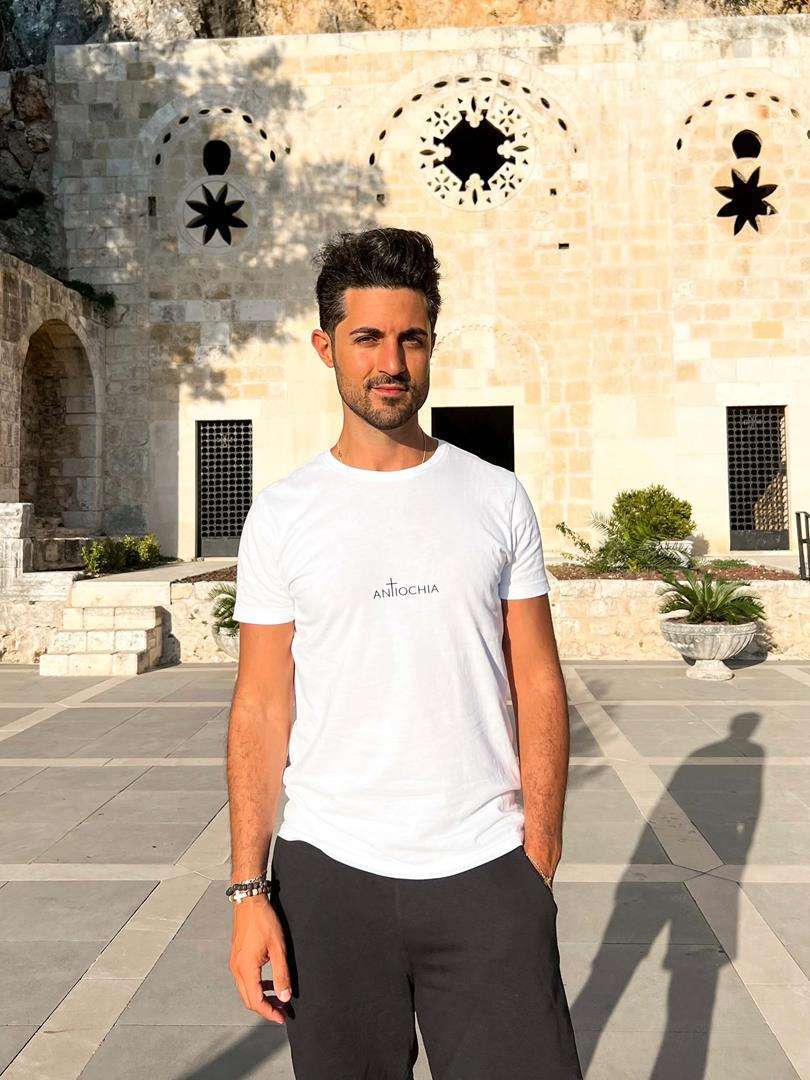 Mann trägt christliches T-Shirt vor historischer Kirche, christliche Mode, Glaube.