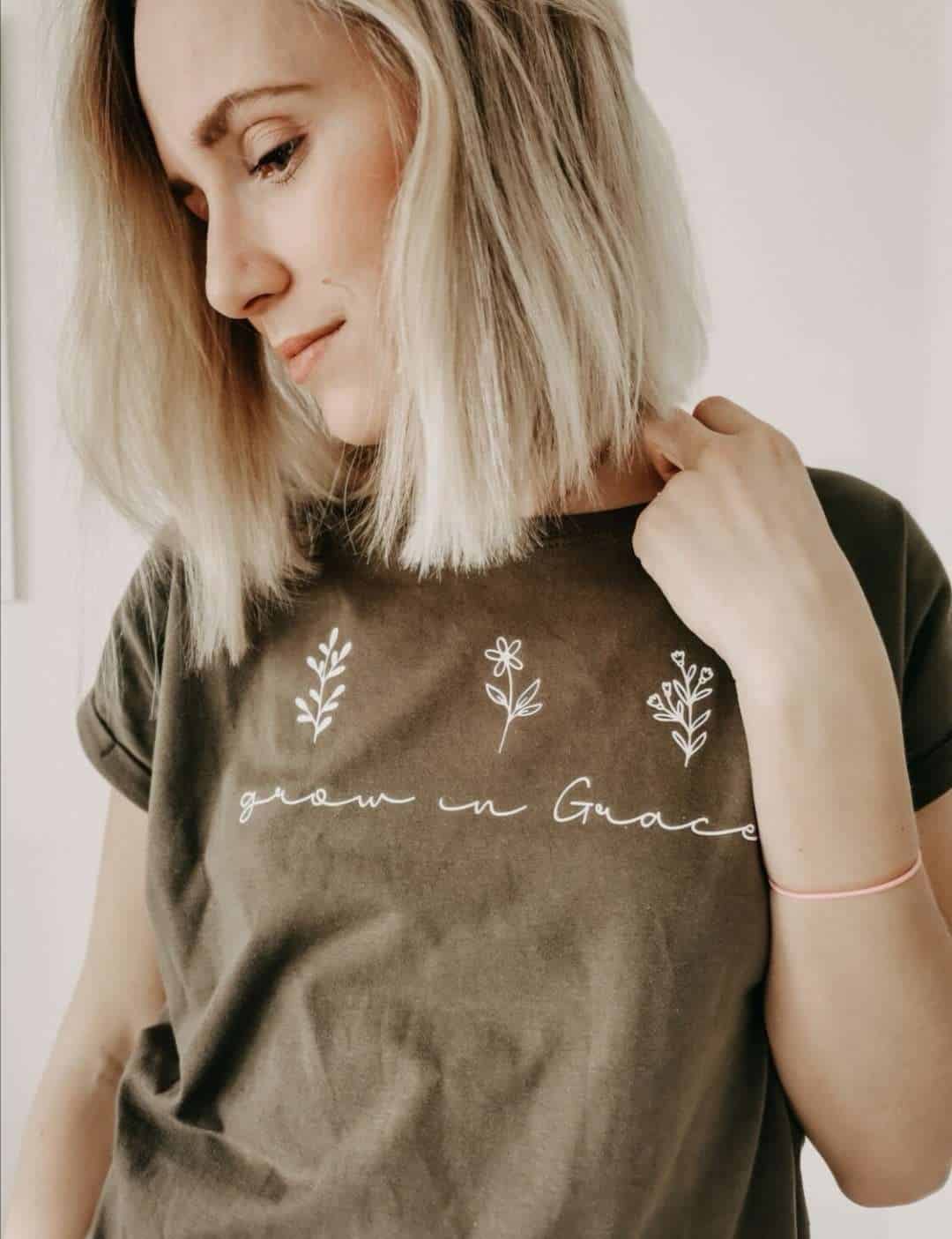 Natürliche Frau trägt christliches T-Shirt mit Blumenmotiv und Bibelvers.