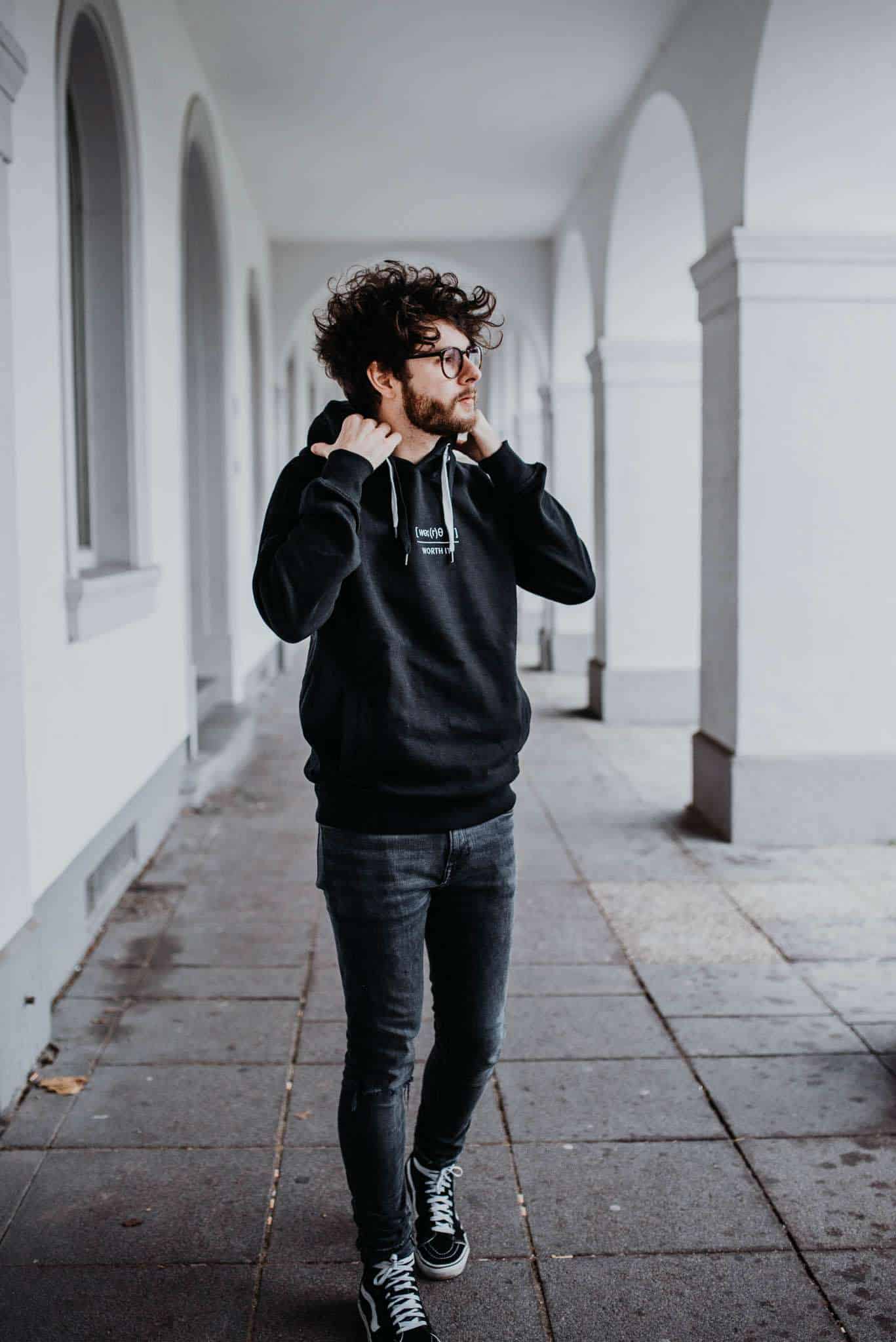 WORTH IT?! Hoodie 8 Moderner junger Mann trägt schwarze Hoodie mit christlichen Motiven, Streetwear Stil.