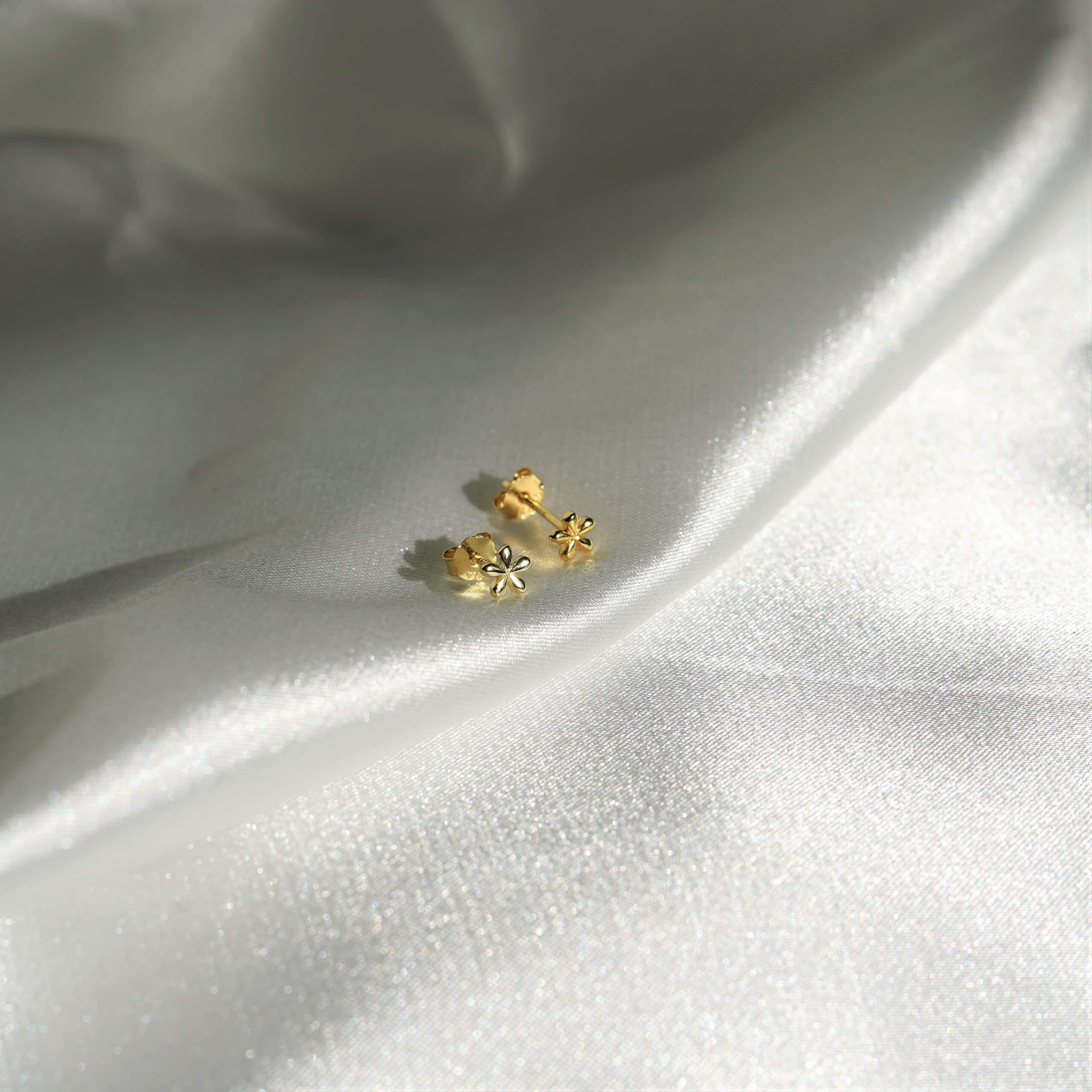 Fleur Mini | Christliche Ohrstecker – 925 Sterling Silber – Gold beschichtet – 4x4 mm 17 Echtselber Ohrringe mit Glockenblumenmotiv auf weißem Satin.