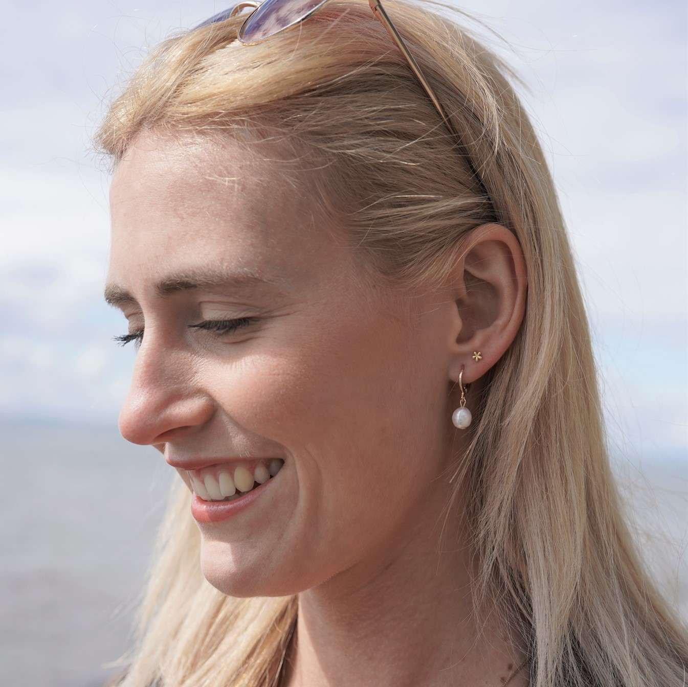 Fleur Mini | Christliche Ohrstecker – 925 Sterling Silber – Gold beschichtet – 4x4 mm 14 Natürliche Schönheit, lachende Frau mit Sonnenbrille am Strand, Outdoor, Lifestyle, Freude.