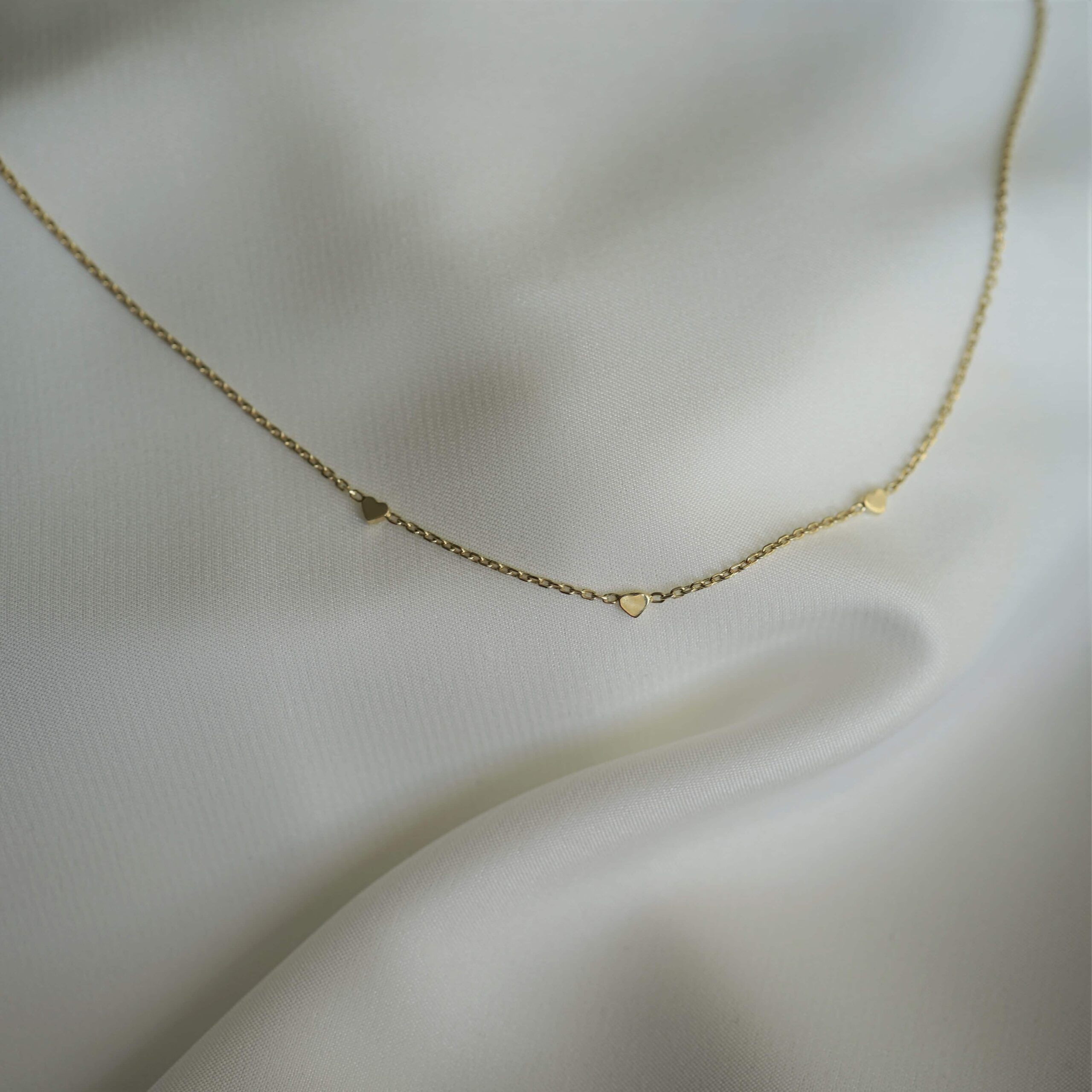 Endless Love | Christliche Kette – 925 Sterling Silber vergoldet – 42cm Länge – gold/roségold/silber 17 Zarte goldene Halskette mit Herzanhängern auf weißem Satin-Hintergrund.