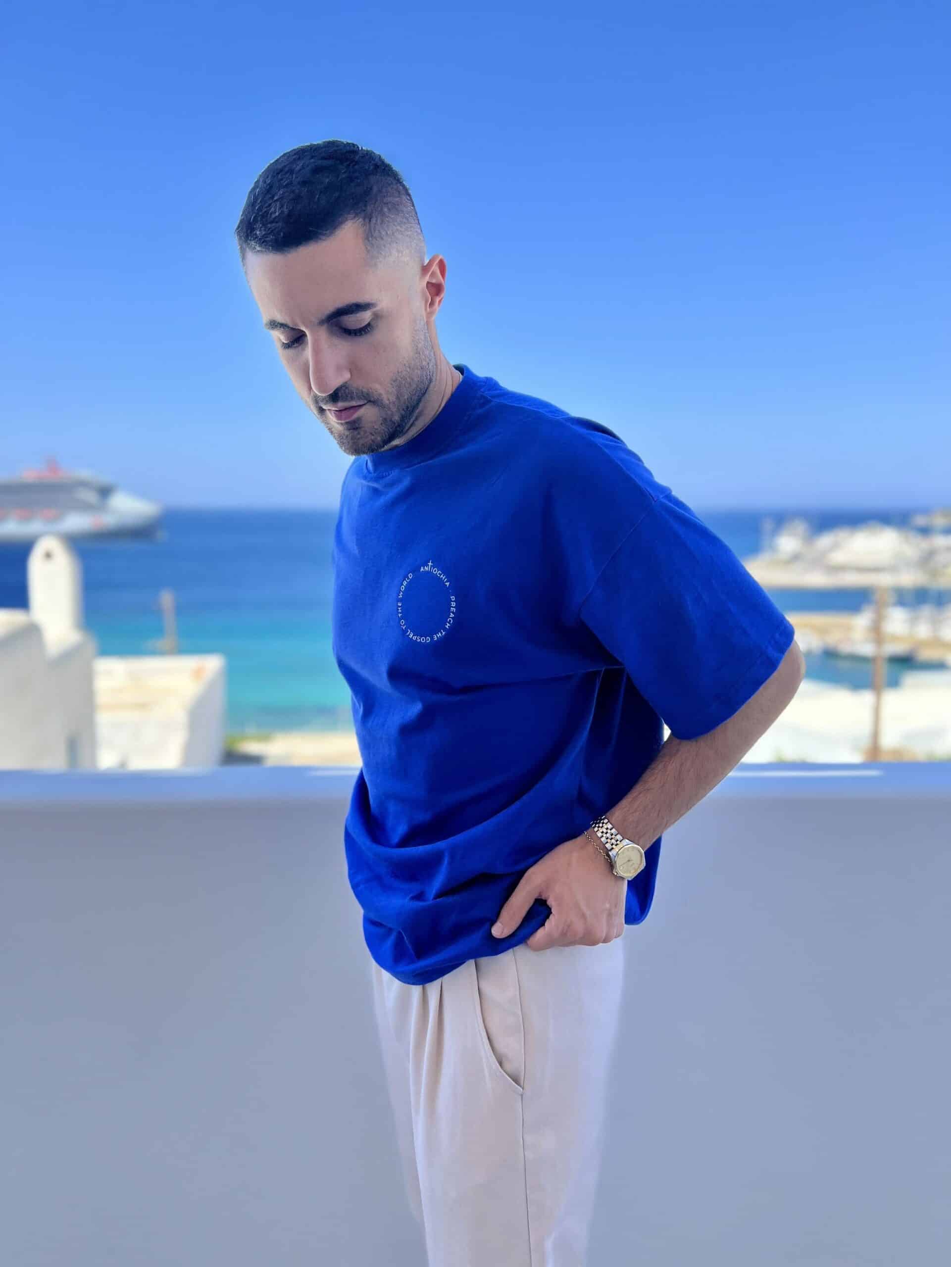 Heavy Oversize T-Shirt - "WORLD" 13 Modischer Christlicher T-Shirt-Träger vor Meereskulisse.
