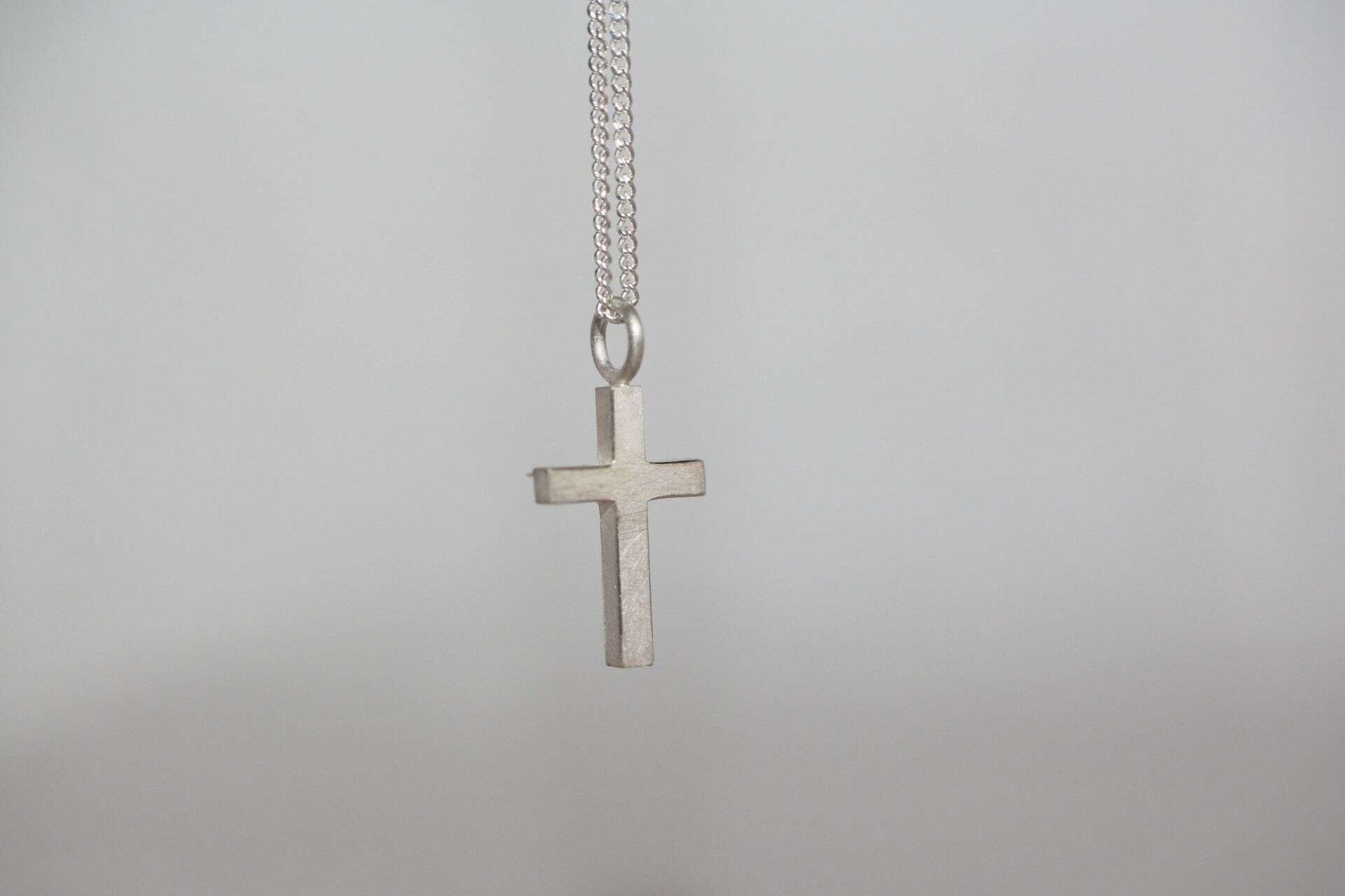 Gsiehe Kette mit Kreuzanhänger, christliches Schmuckstück, religiöser Hinweis.