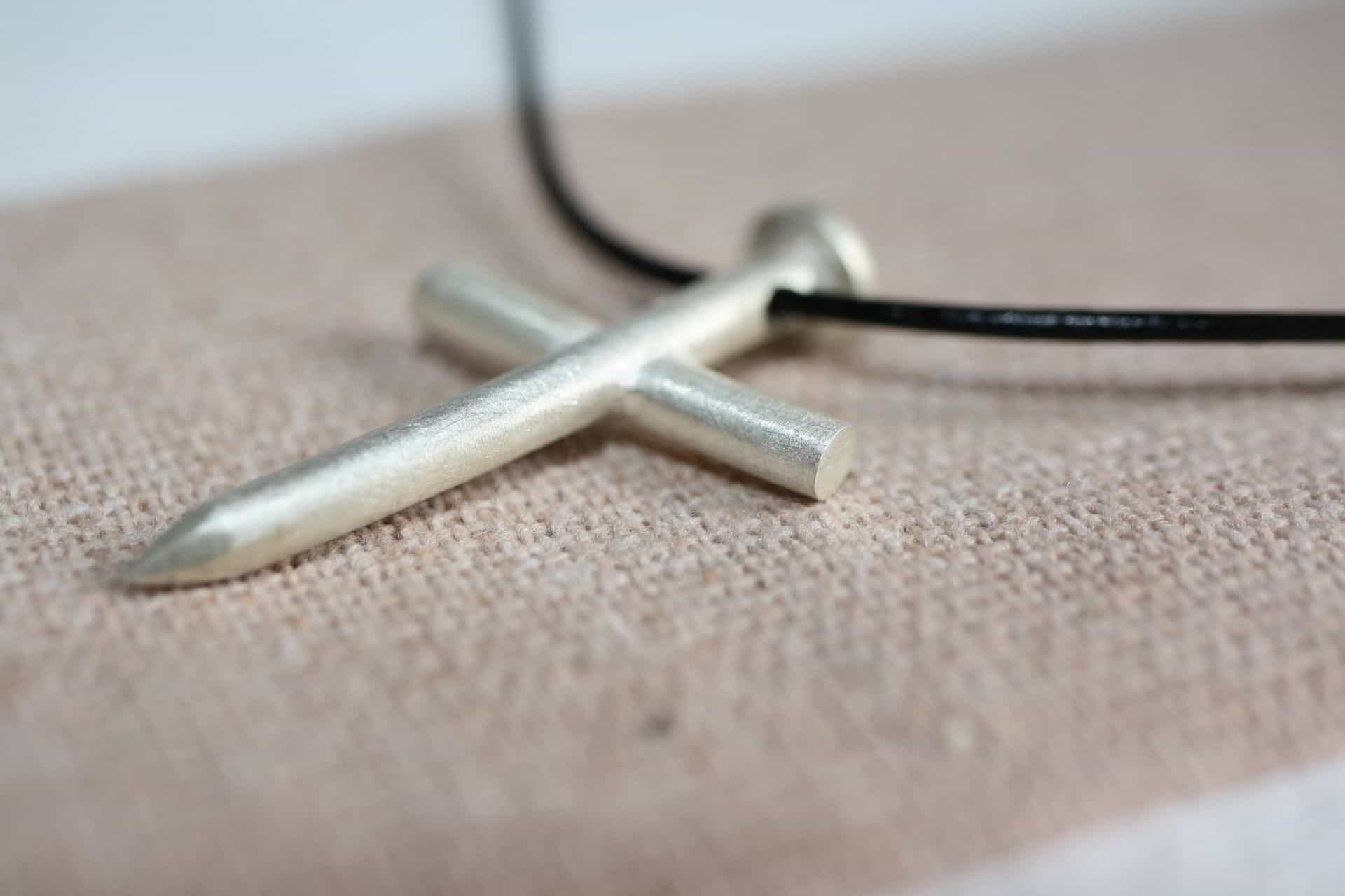 Kreuz - JUST JESUS 3 Glaube Kreuz Anhänger aus Metall auf braunem Stoffliebe christliche Symbolik und Schmuck.