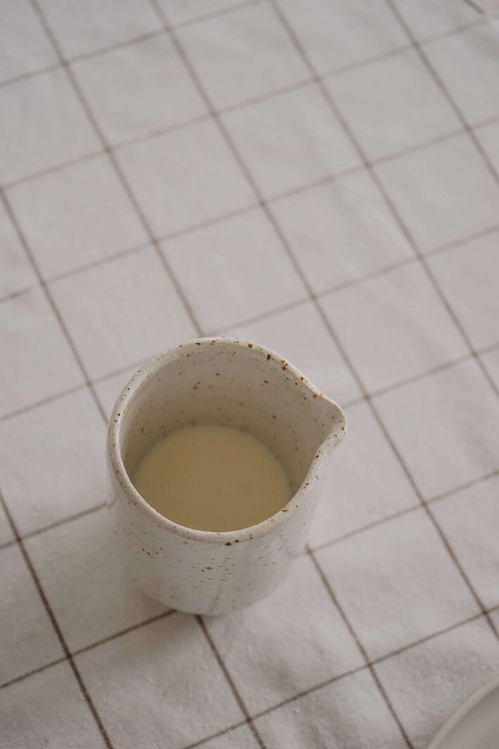 Kännchen mit passendem Print A3 2 Nachfüllende Milch in einer Keramik-Kanne auf einer Fliesenfläche.