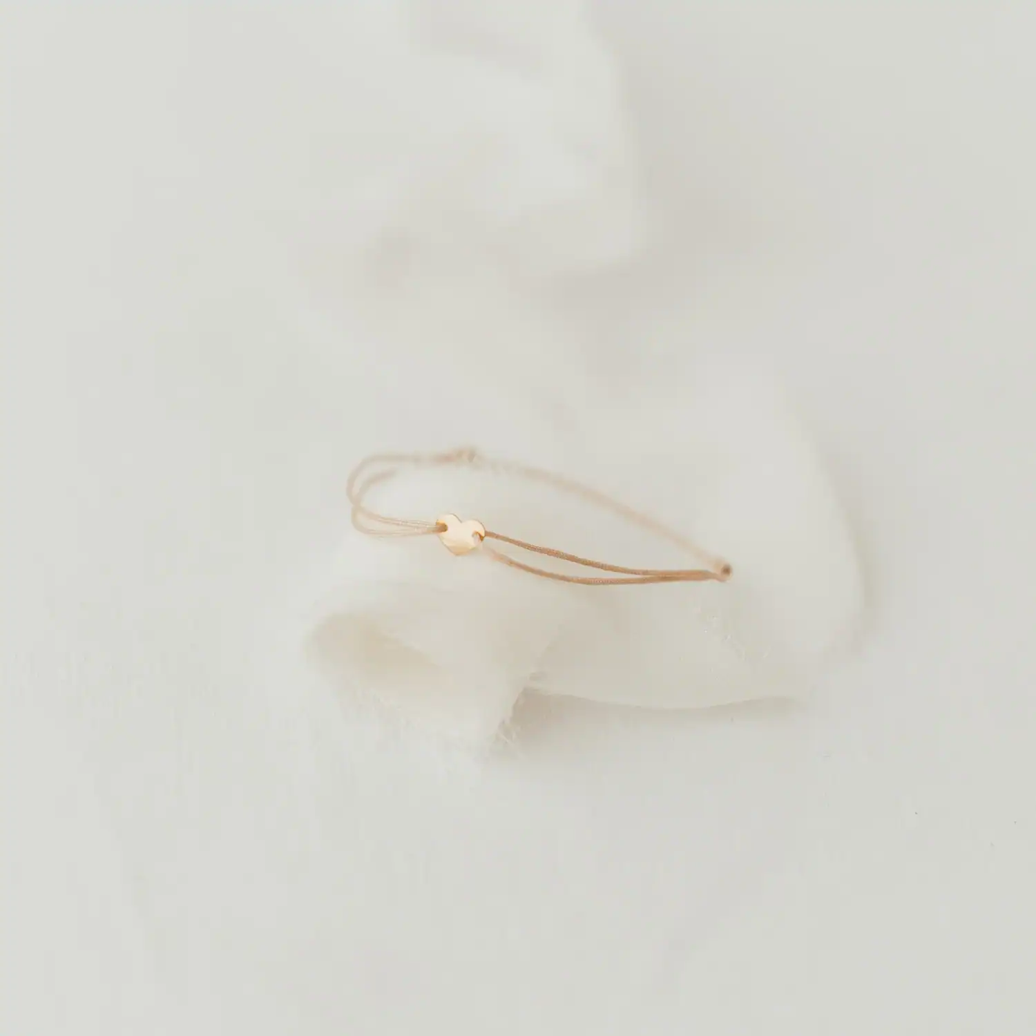 Armband KOSTBAR Herz 2 Minimalistisches Christenschmuckarmband auf weißem Stoffhintergrund.