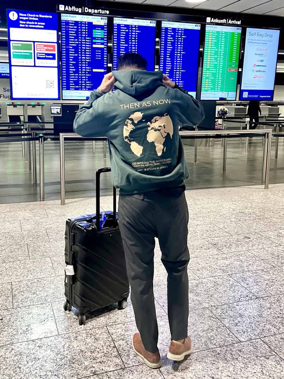 Oversize Hoodie - "World" 14 Zweiter handgepäck trolly auf Flughafen mit Abflug und Ankunft Anzeigetafeln.