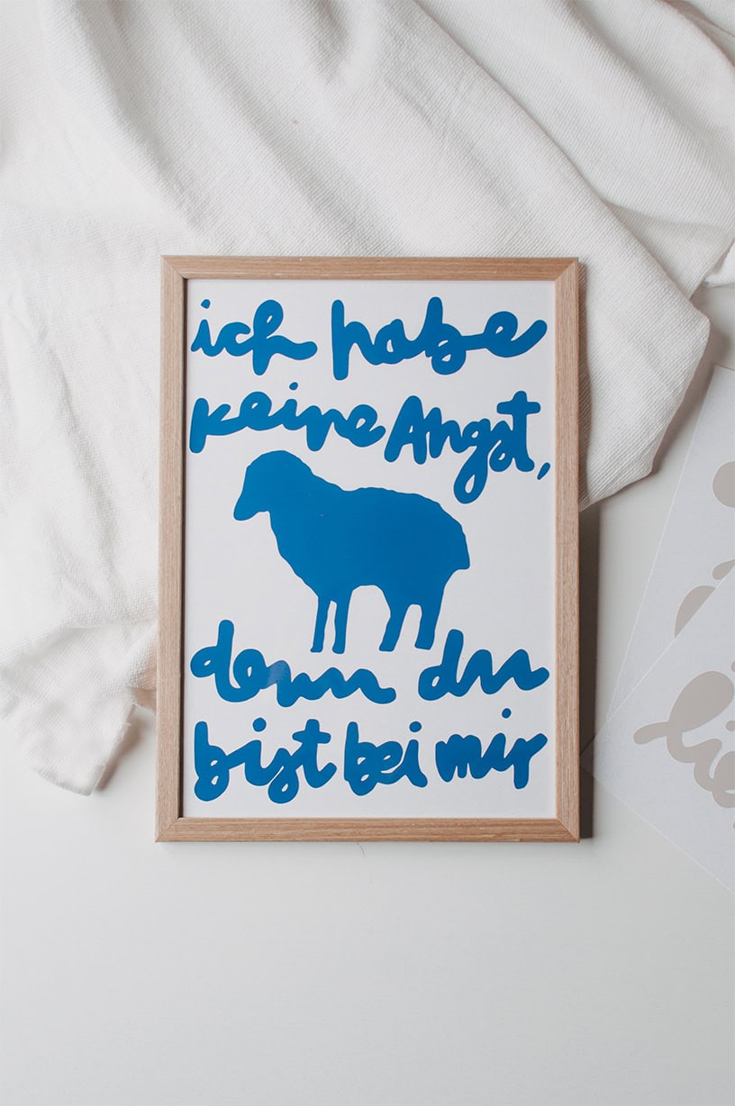Seitlicher Blick auf christliches Wandbild mit Bibelspruch und Schafmotiv, Flatlay, geistliche Dekoration, Glaube, religiöse Kunst.