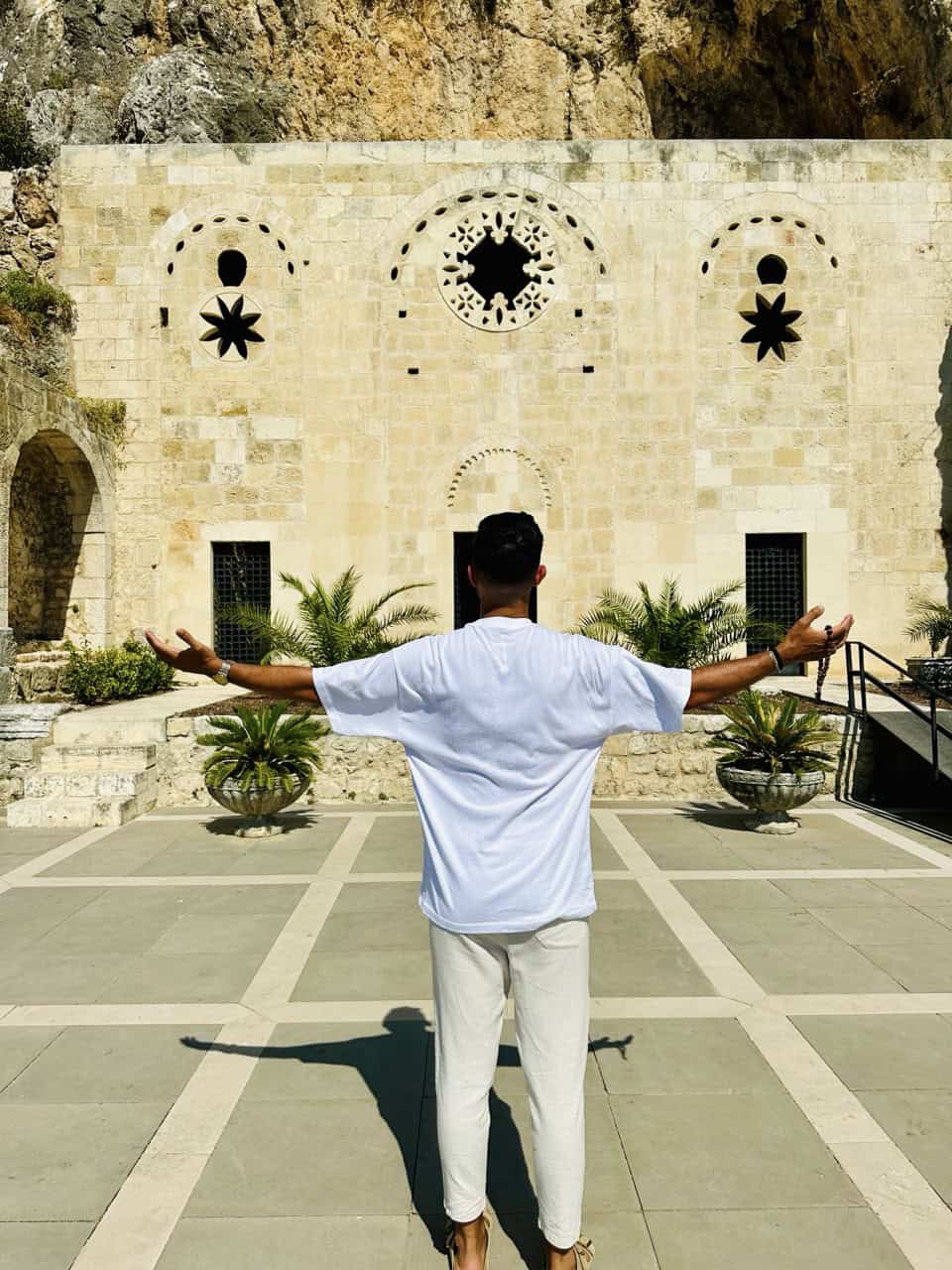 Essential Oversize T-Shirt ALLWHITE - "LIGHT" 14 Betender Mann vor christlicher Kirchenfassade mit Symbolen, Glaube und Spiritualität.