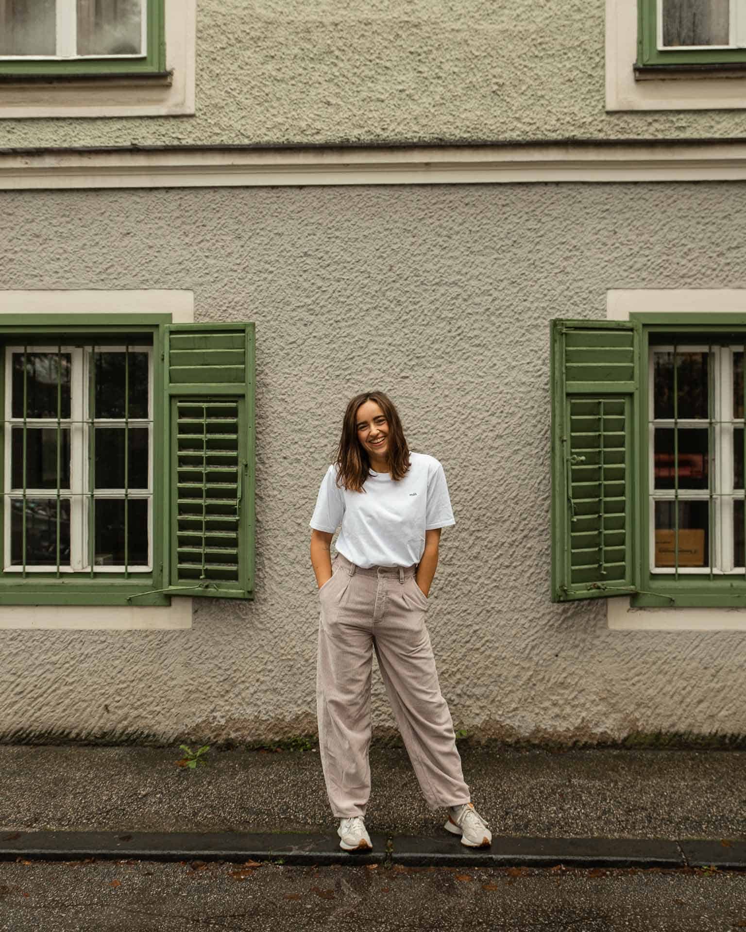 mäh / tshirt / psalm 23 13 Moderne junge Frau vor grüneshölzernen Fensterläden, urbaner Streetstyle, natürliche Beleuchtung.