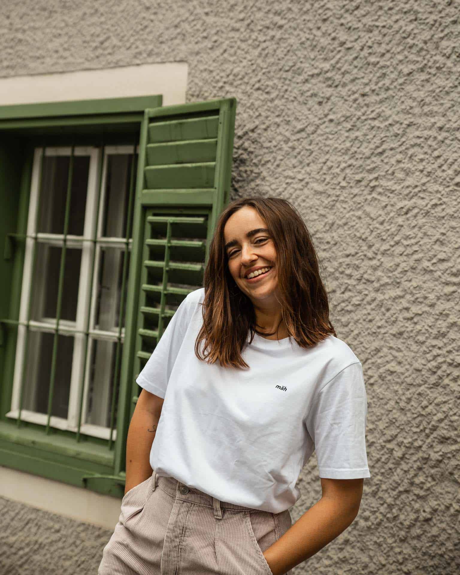 mäh / tshirt / psalm 23 12 Fröhliche junge Frau mit weißen T-Shirt vor grüner Fensterläden auf Mookho.de.