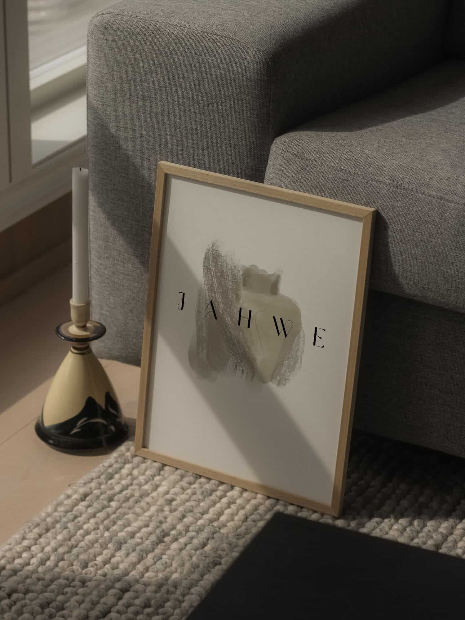 Poster "Jahwe" 12 Inhalt des Bildes: Ein Bilderrahmen mit "JAHWE" Schrift auf dem Boden neben einem Kerzenständer, an einer Couch.