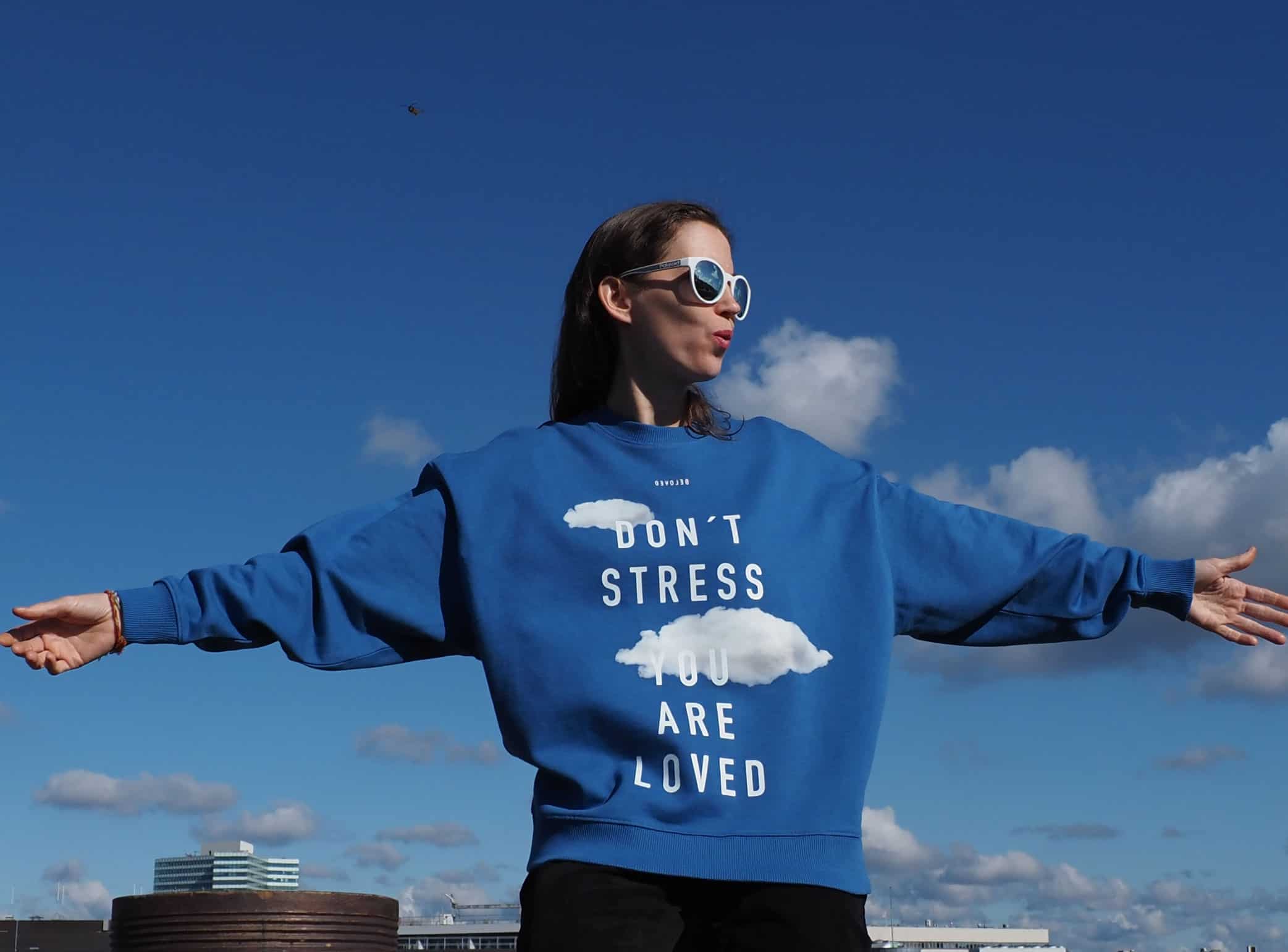 Stressfreier Mensch mit Botschaft auf Sweatshirt, metaphorische Natur, Himmel, Mode, Lifestyle.