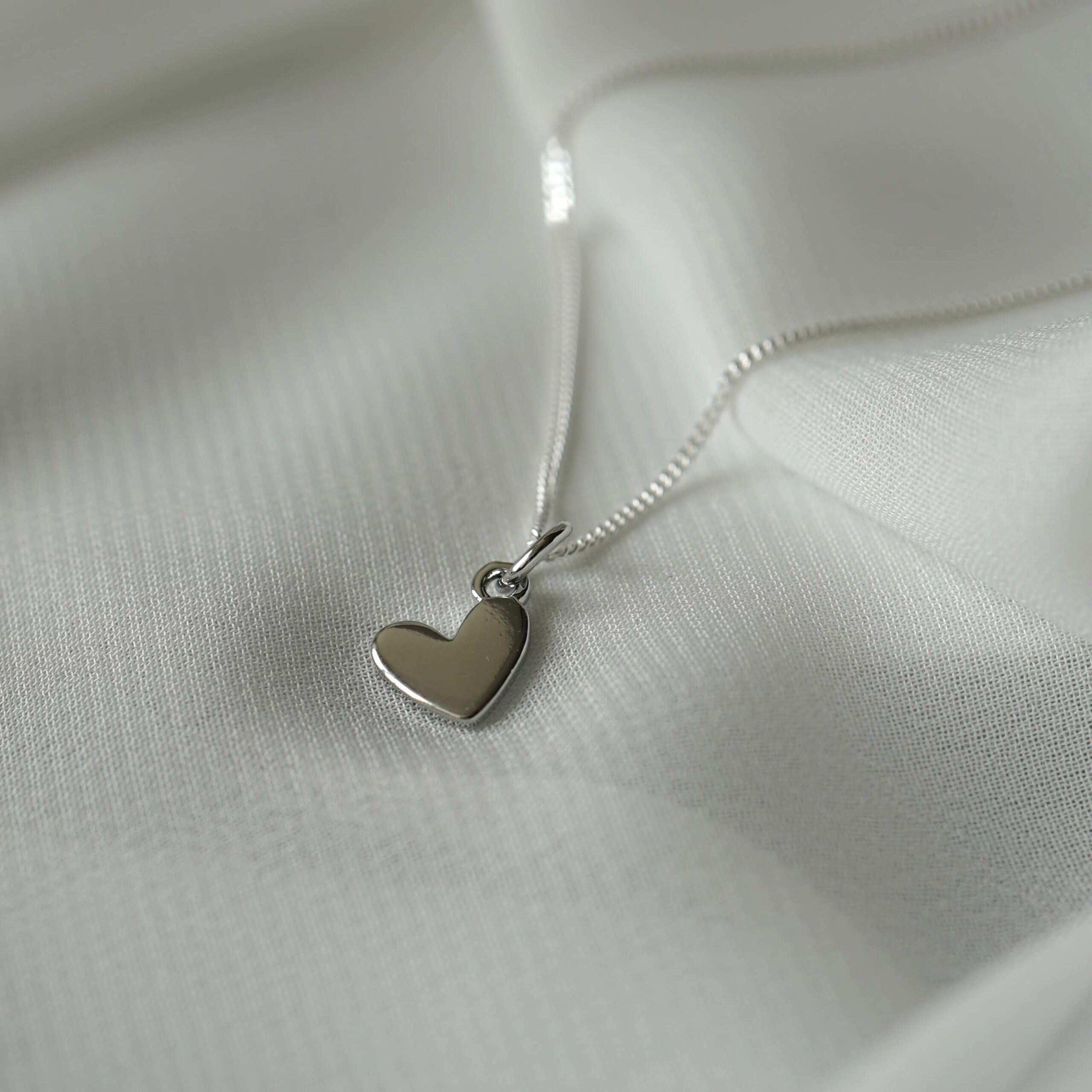Love | Christliche Kette – 925 Sterling Silber – Messing 18k vergoldet – deutsche Silberschmiede 12 Schmuckanhänger in Herzform auf weißem Stoff, christliche Mode, Geschenke für Christen.