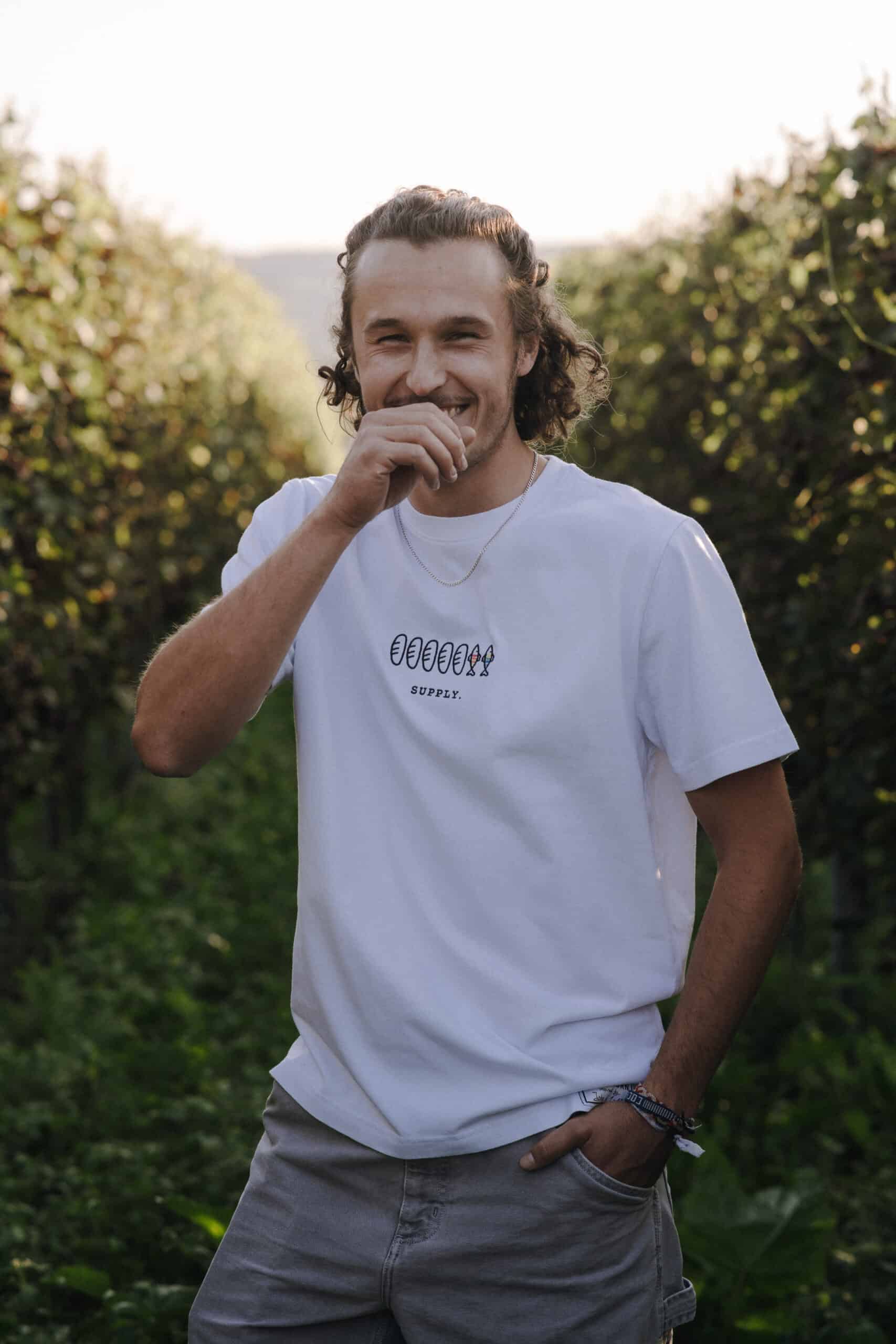 Menschenfreundlicher Mann trägt T-Shirt mit Bibel-Motiv, Outdoor, christlicher Lifestyle, positive Stimmung.