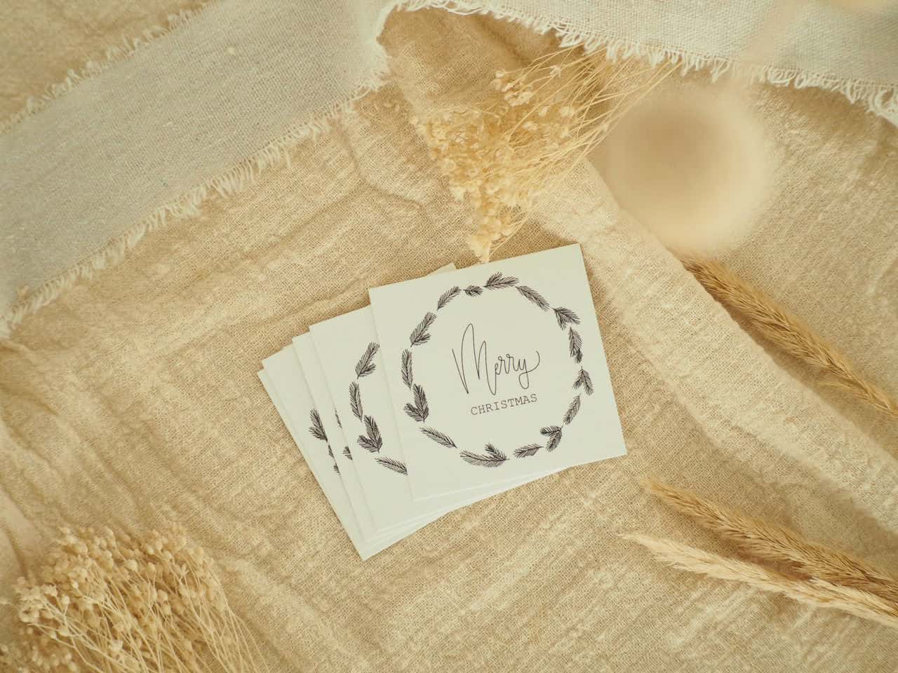 Handgemachte Weihnachtskarten mit christlichem Gruß auf natürlichem Stoffhintergrund.