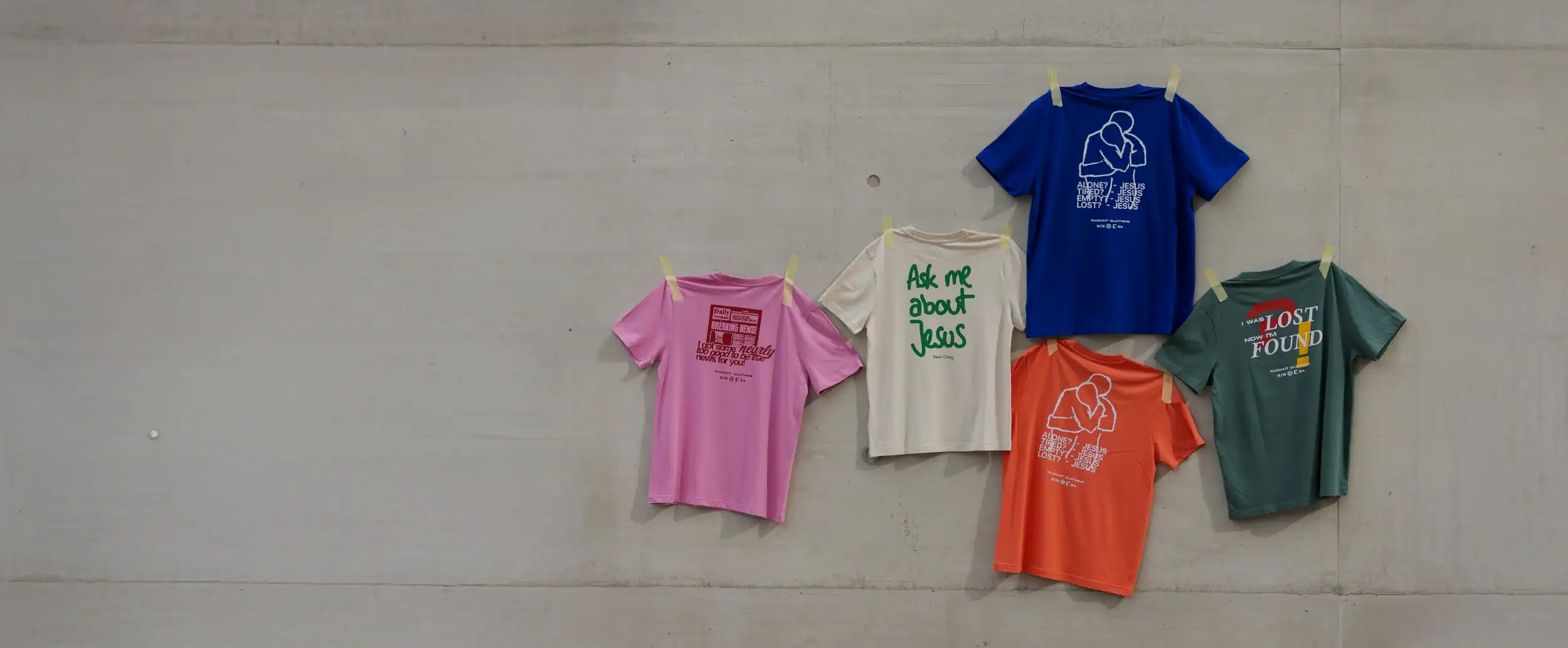 Modische christliche T-Shirts an einer Betonwand zum Verkauf bei mookho.de.