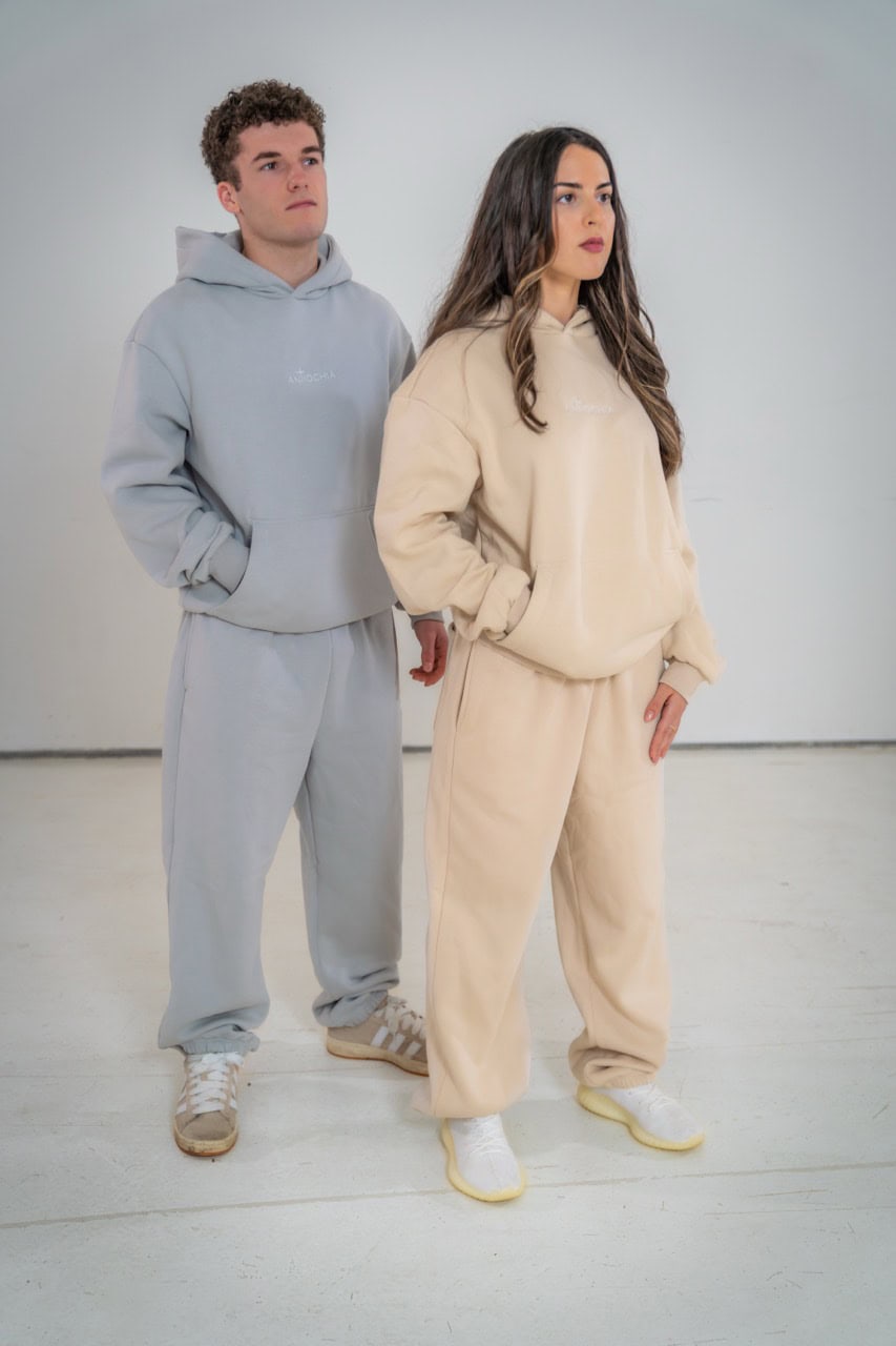 Essential Hoodie Oversized - "Petrus" 14 Freundliches junges Paar trägt bequame Pastell-Hoodies und Jogginghosen, Streetwear, stylisch.