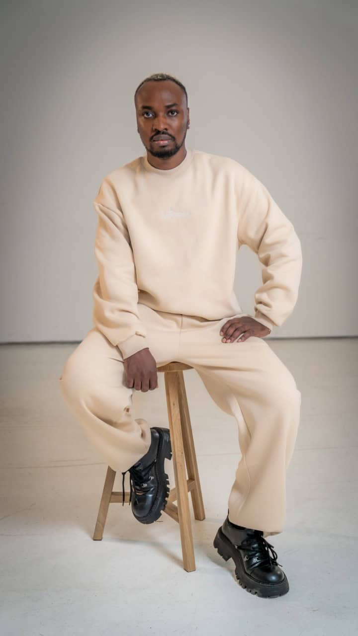 Essential Sweatshirt Oversized - "Paulus" 17 Moderner Mann in beiger Kleidung auf Hocker, christliche Mode, christliche Marken, Glaube.