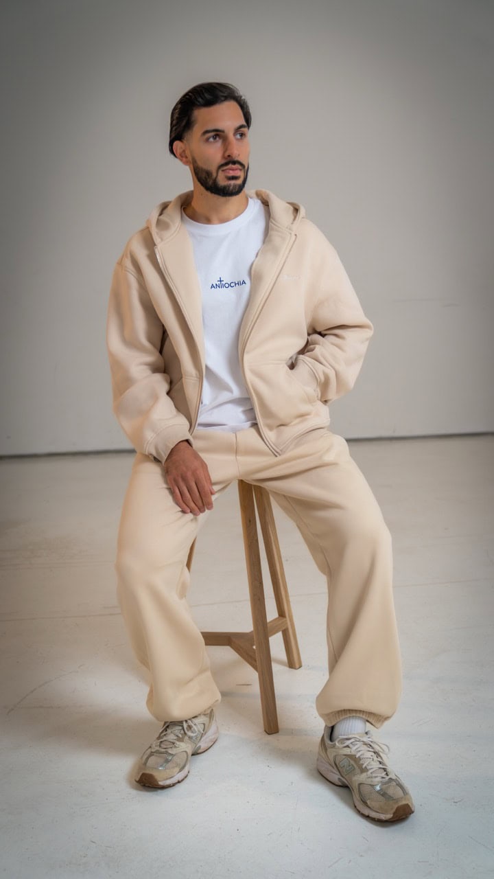 Essential Zipper - "Thomas" 15 Moderner Mann in beigem Joggingoutfit mit christlichem T-Shirt, Casual Style, Mode.