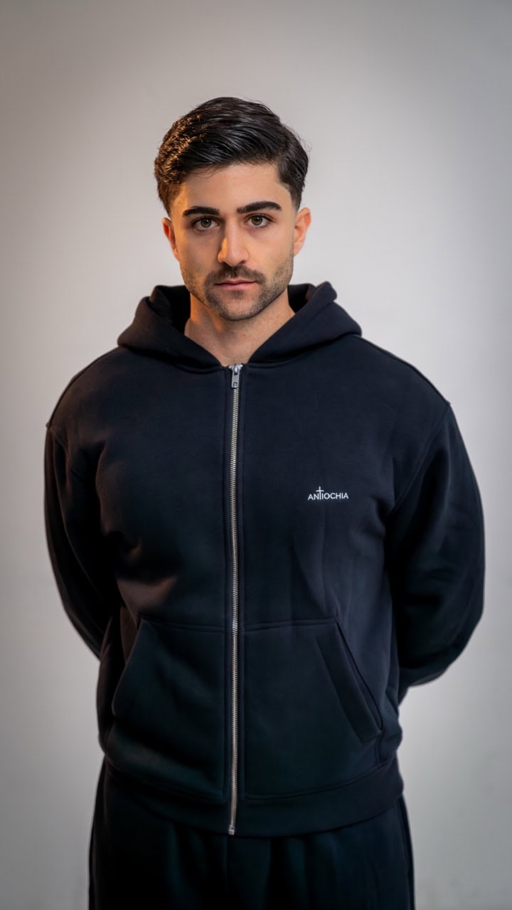 Essential Zipper - "Thomas" 17 Moderner Mann trägt schwarze Hoodie mit christlichem Logo auf Mookho.de.