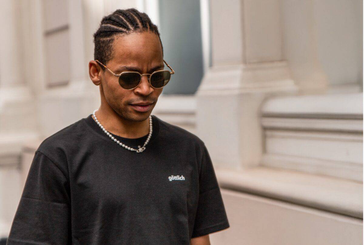 Model mit Sonnebrille trägt schwarzes christliches Shirt mit der Aufschrift „göttlich“