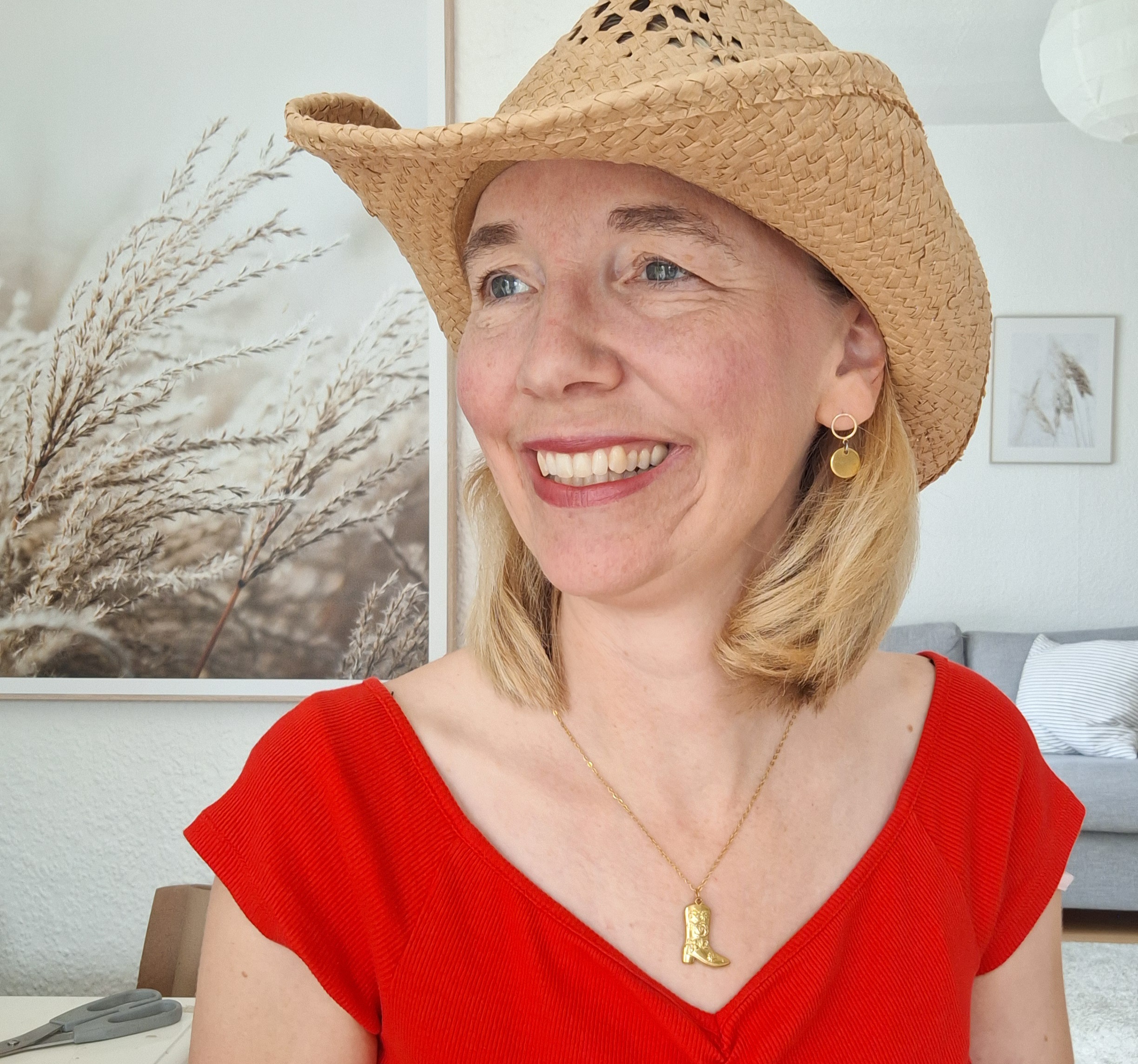 Goldkette "Cowboystiefel" 5 Christliche Frau mit Strohhut und rotem Kleid, fröhlich, in modernem Zuhause, Lifestyle, positive St.