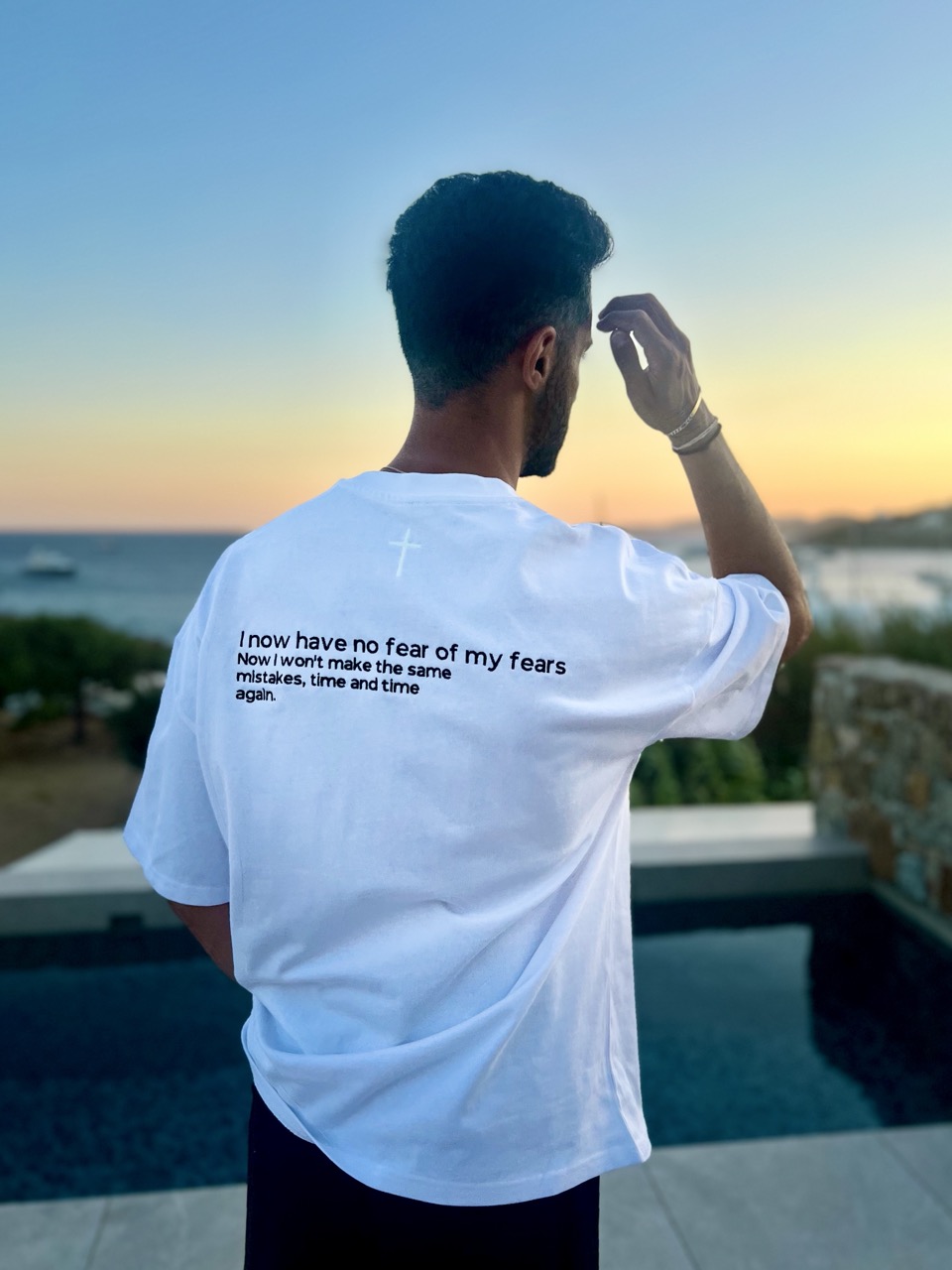 Heavy Oversize T-Shirt - "No Fear" 17 Der Mann am Strand mit Sonnenuntergang, trägt ein weißes T-Shirt mit Bibelvers, christliche Inspirat.