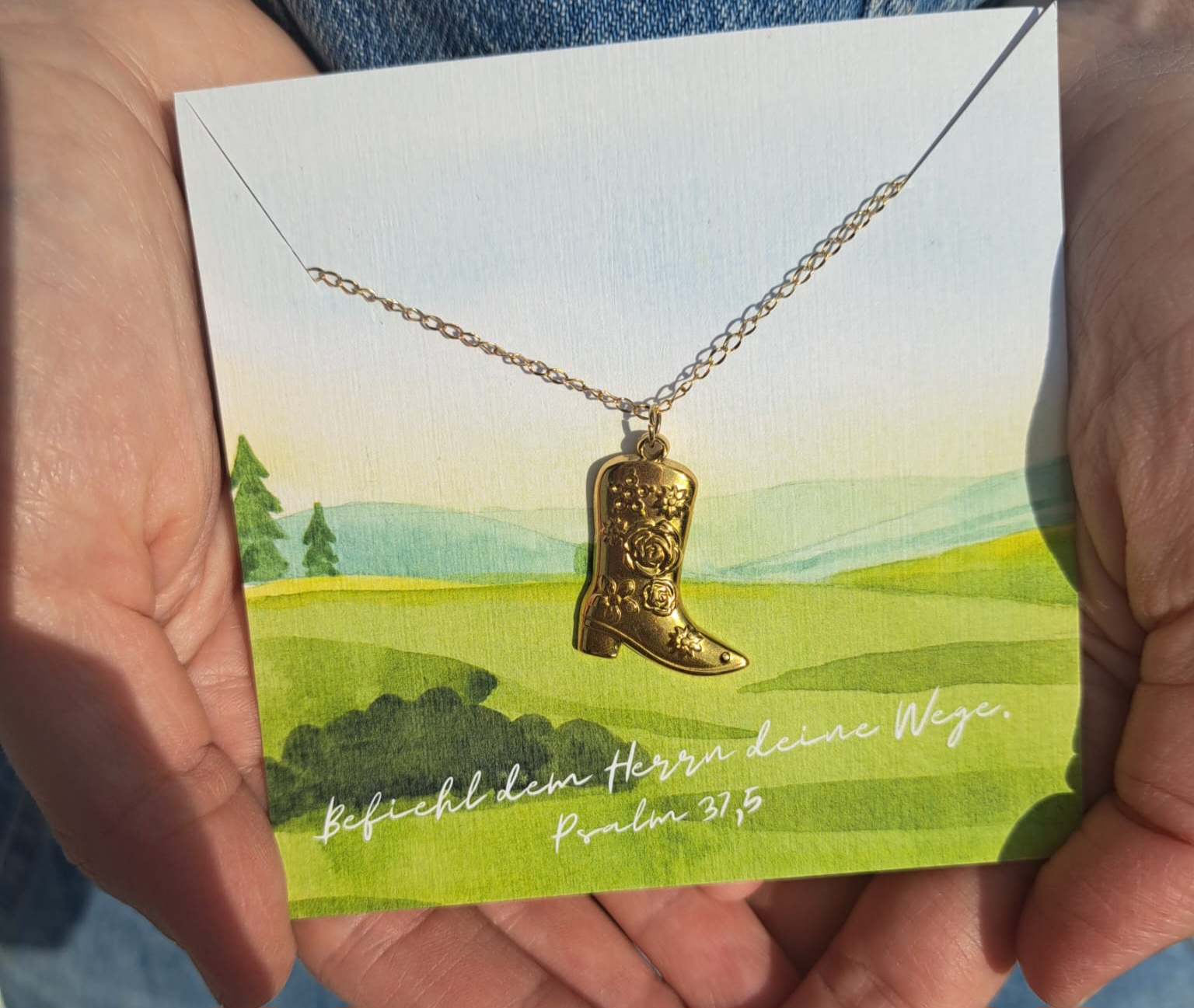 Psalm 37,5 auf einer Grußkarte mit goldener Schuh-Halskette, christliche Botschaft.