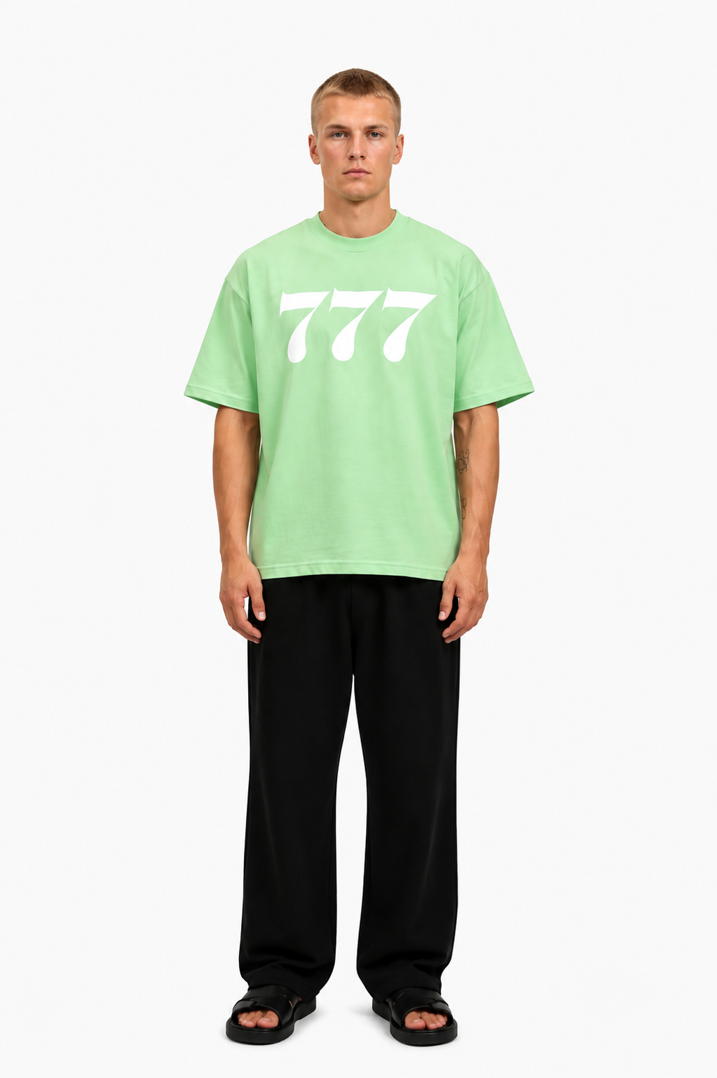 Ein junger Mann trägt ein grünes T-Shirt mit weißen "777" aufdruck, lässig und modern.