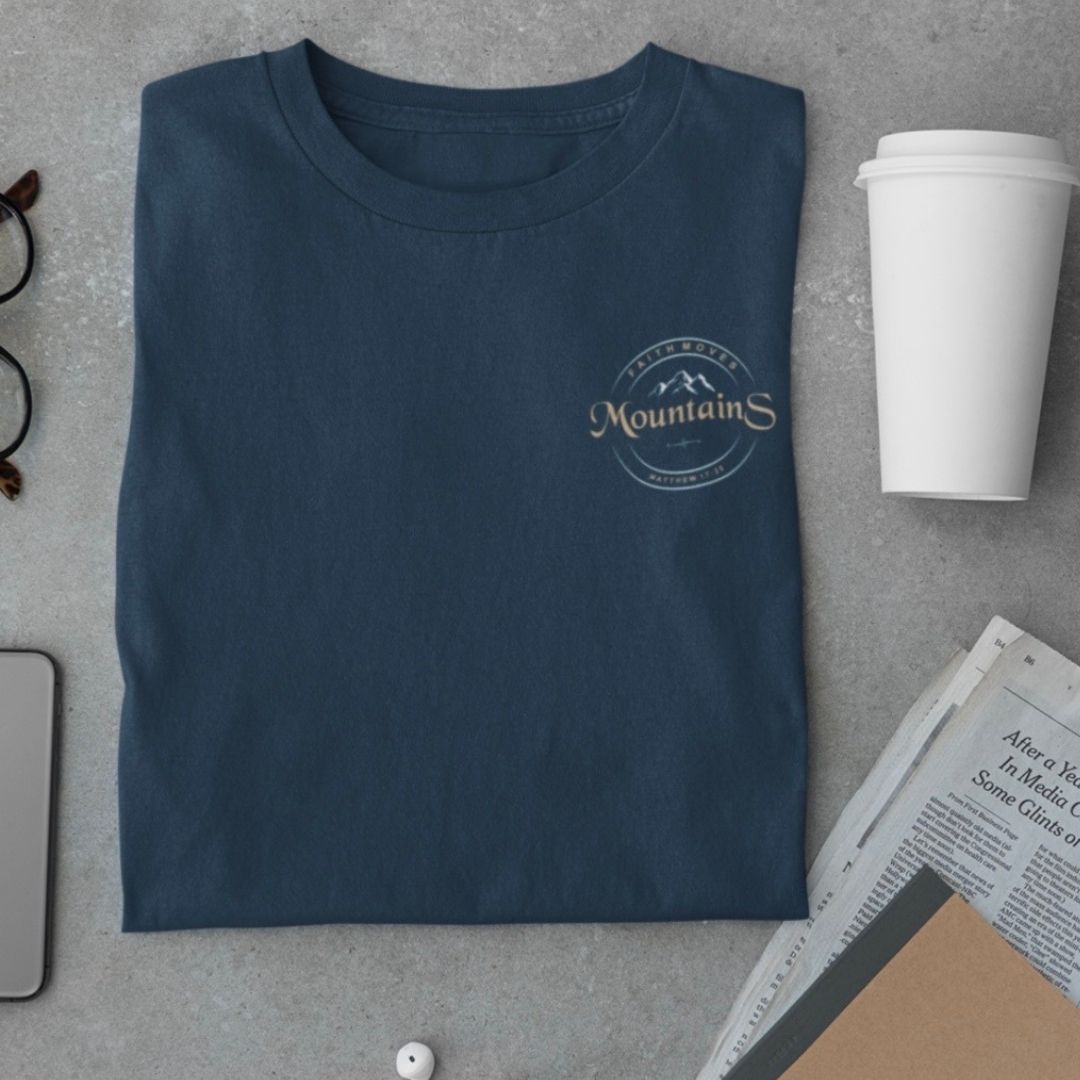 Faith moves Mountains Matthäus 17,20 - hochwertiges T-Shirt Bio Baumwolle 10 MountainS T-Shirt mit christlichem Logo, auf grauem Hintergrund, mit Kaffeebecher und Zeitung.