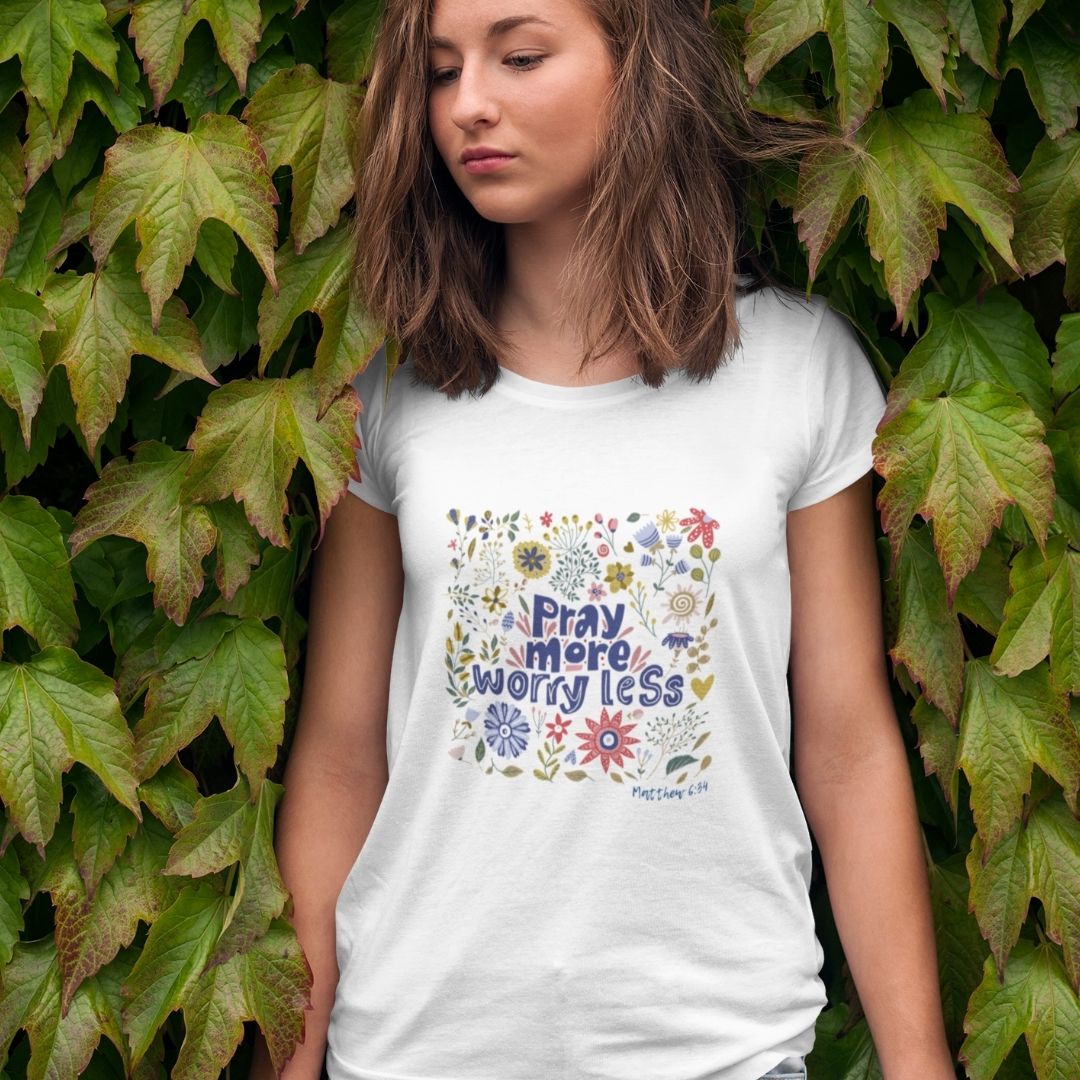 Pray more -worry less Mutmachendes T-Shirt Bio Baumwolle 13 Bildausschnitt einer jungen Frau mit T-Shirt mit dem Aufdruck "Pray more worry less" vor einer grüne.