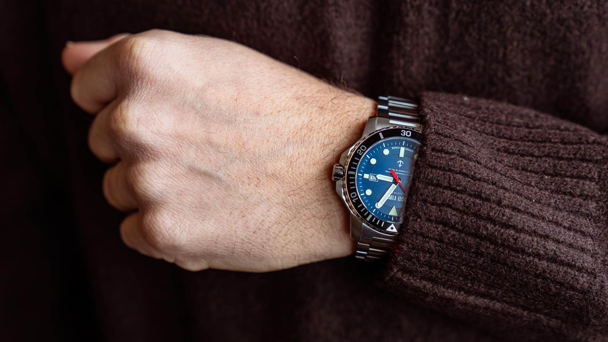 OCEAN OF FAITH - Schweizer Uhren inspiriert vom Glauben - Blau Edelstahl 5 Mann trägt Armbanduhr mit blauer Lünette und schwarzem Armband.